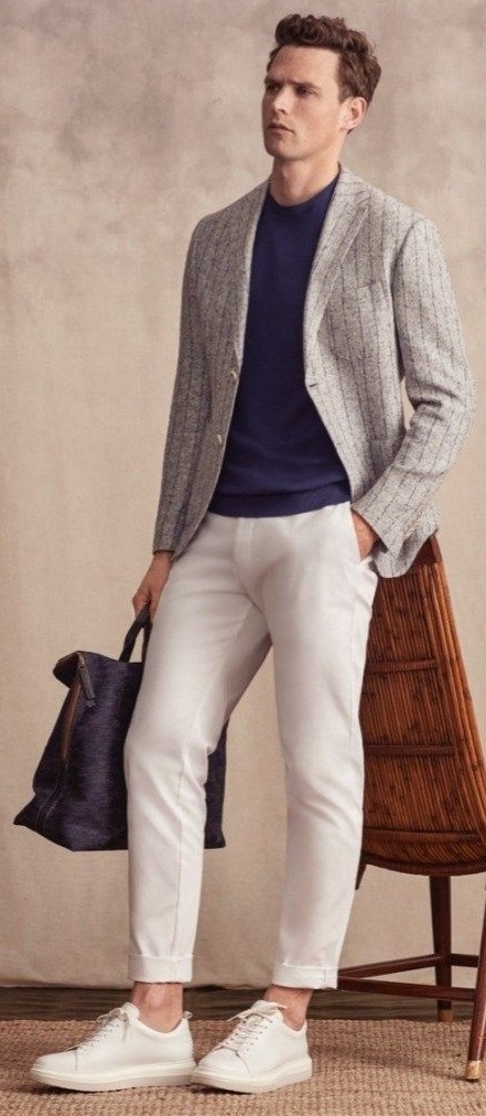 Grey suit with navy blue t-shirt and cream chinos and white shoes, holding a bag