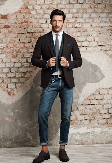 dark brown suit with a white undershirt and grey tie paired with jeans and boots