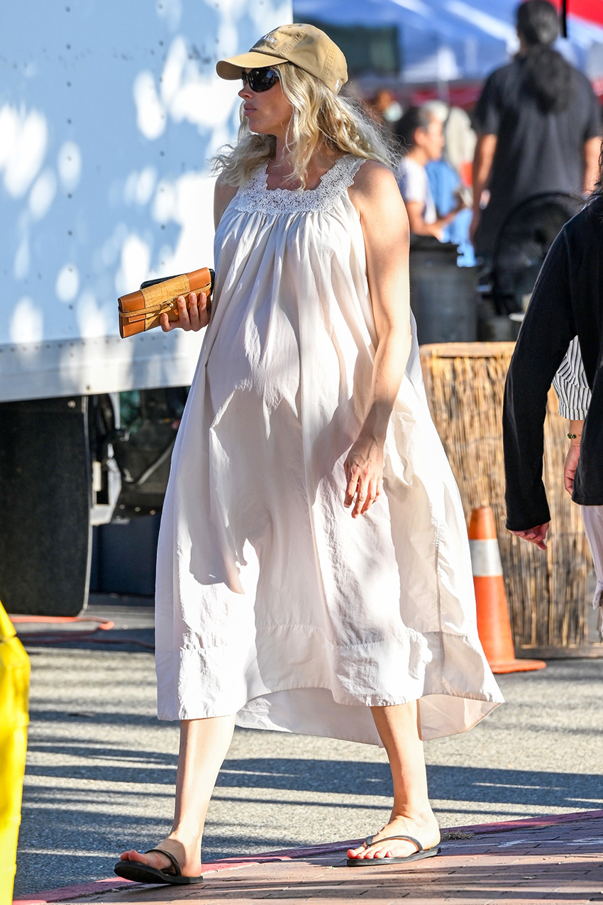 Elsa Hosk wearing a white sleep dress and flip-flops with a tan baseball cap