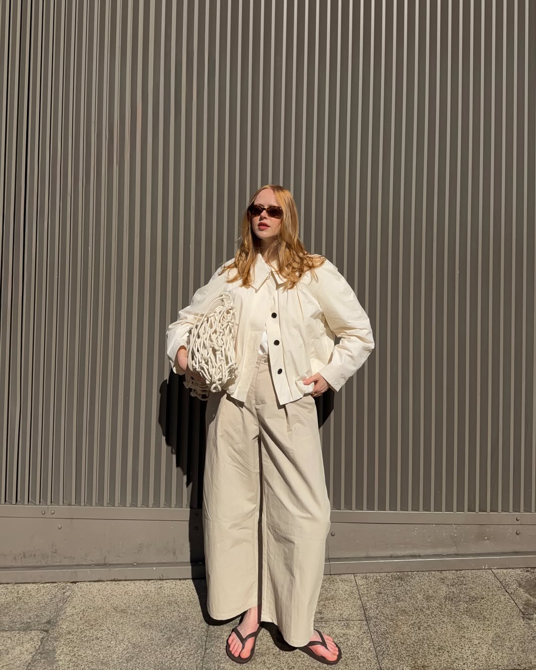 Influencer Holly Rebecca White wearing beige barrel leg trousers, cotton jacket and rope bag.