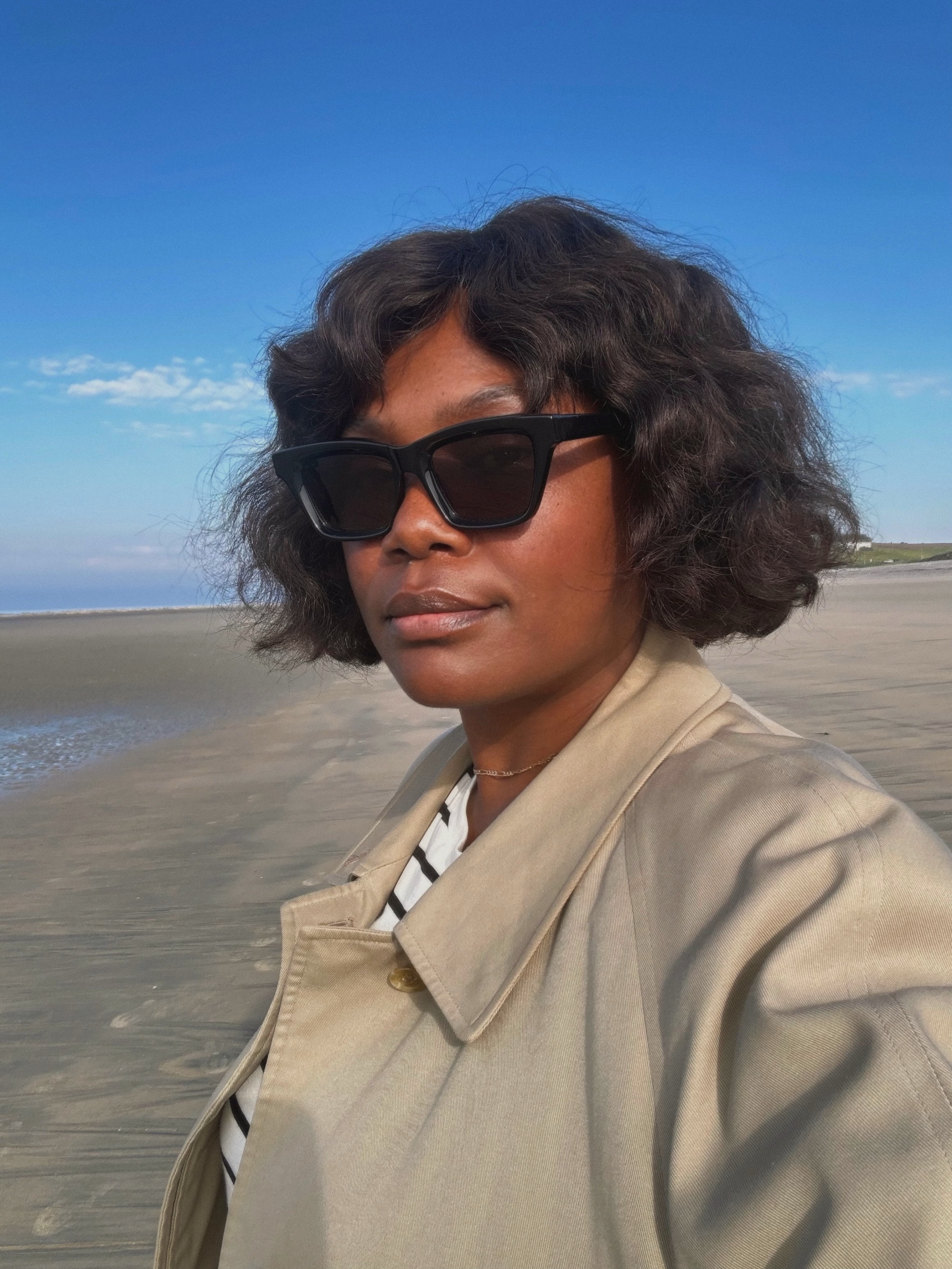 Creator @frannfyne taking a selfie on the beach with a tousled, wavy bob