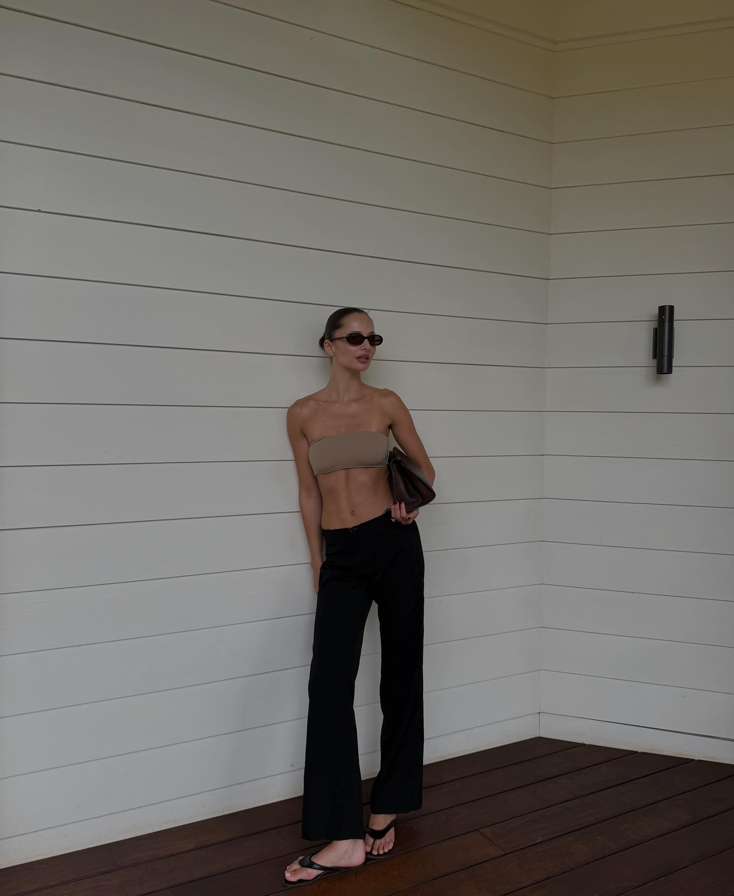 Pia Mance wearing a strapless tan bikini with black pants and flip-flops.