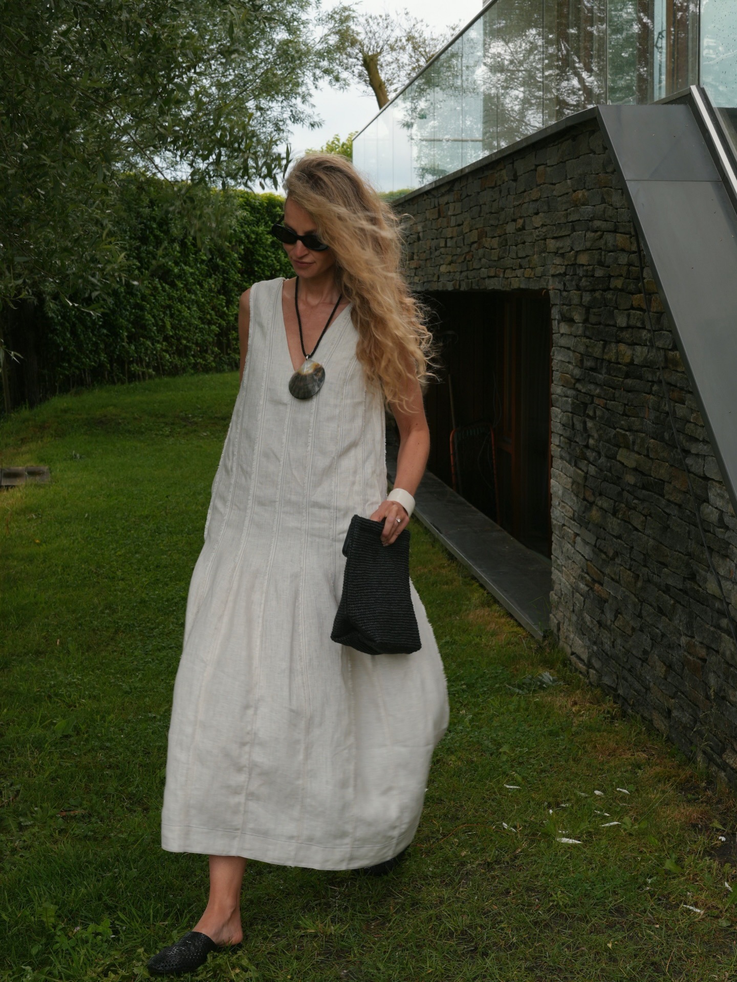 Woman wears white COS dress, shell necklace, black bag and black shoes