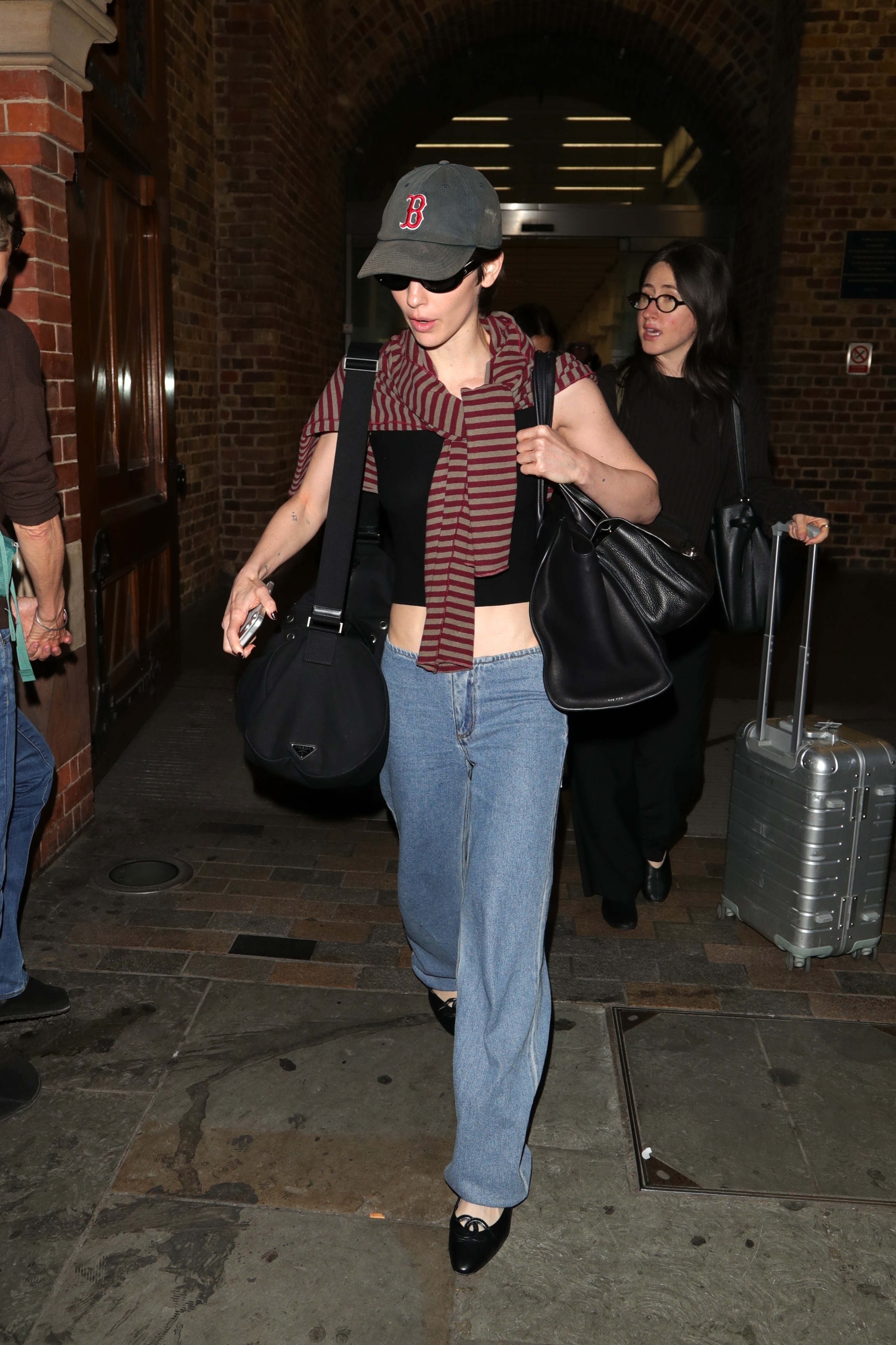 Gracie abrams wears a boston hat, stripe sweater, black tank, still here sport jeans, and black ballet flats.