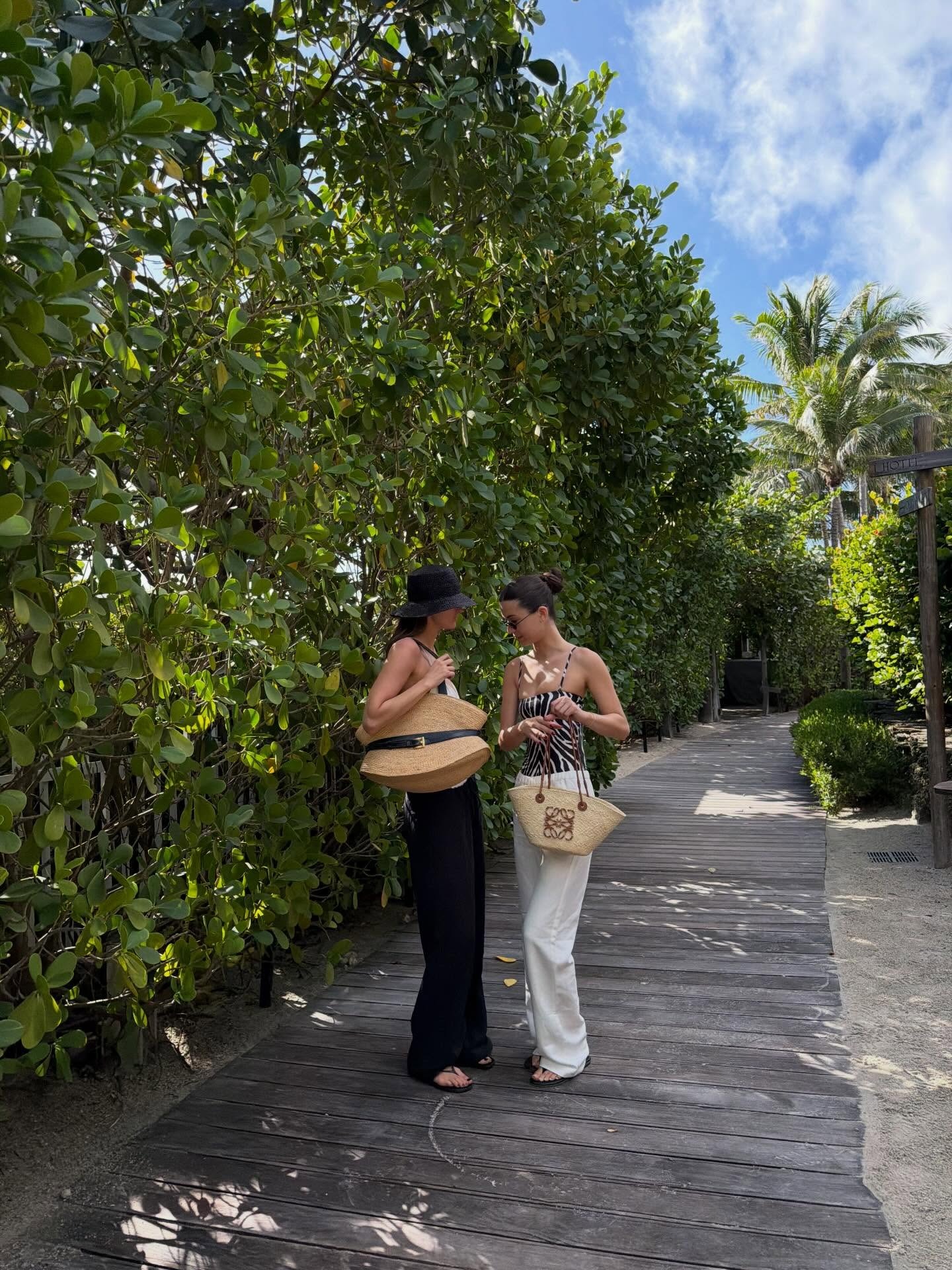 Coco Schiffer and a friend wearing a one-piece swimsuit with white beach pants.