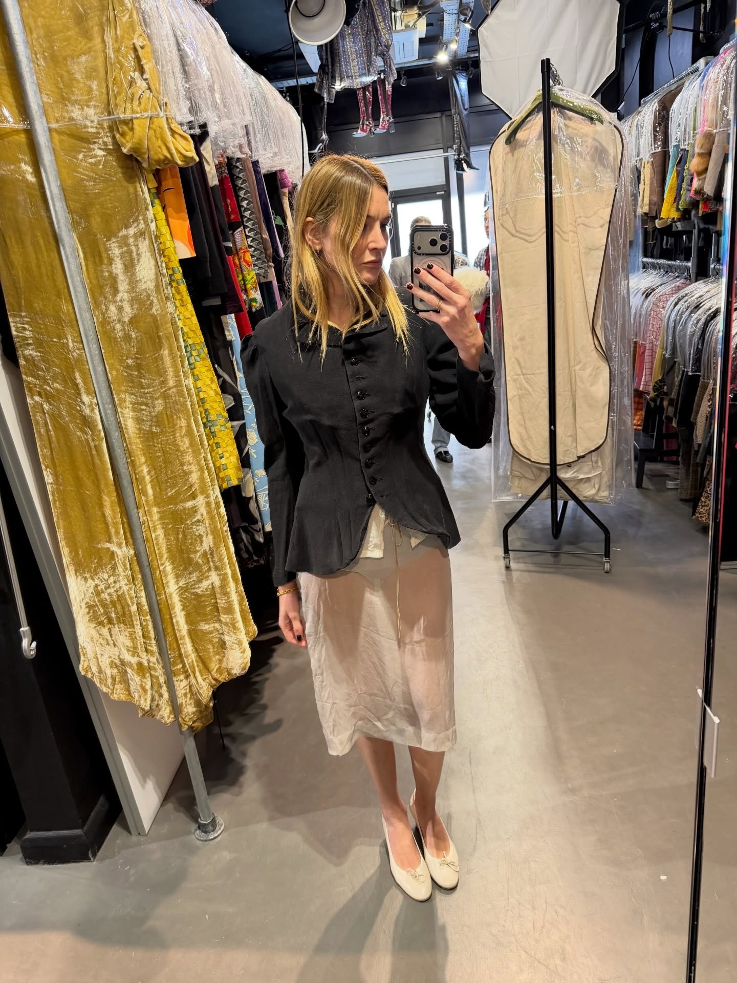 Camille Charriere wearing a black sculpted blazer with a sheer skirt and ballet flats.