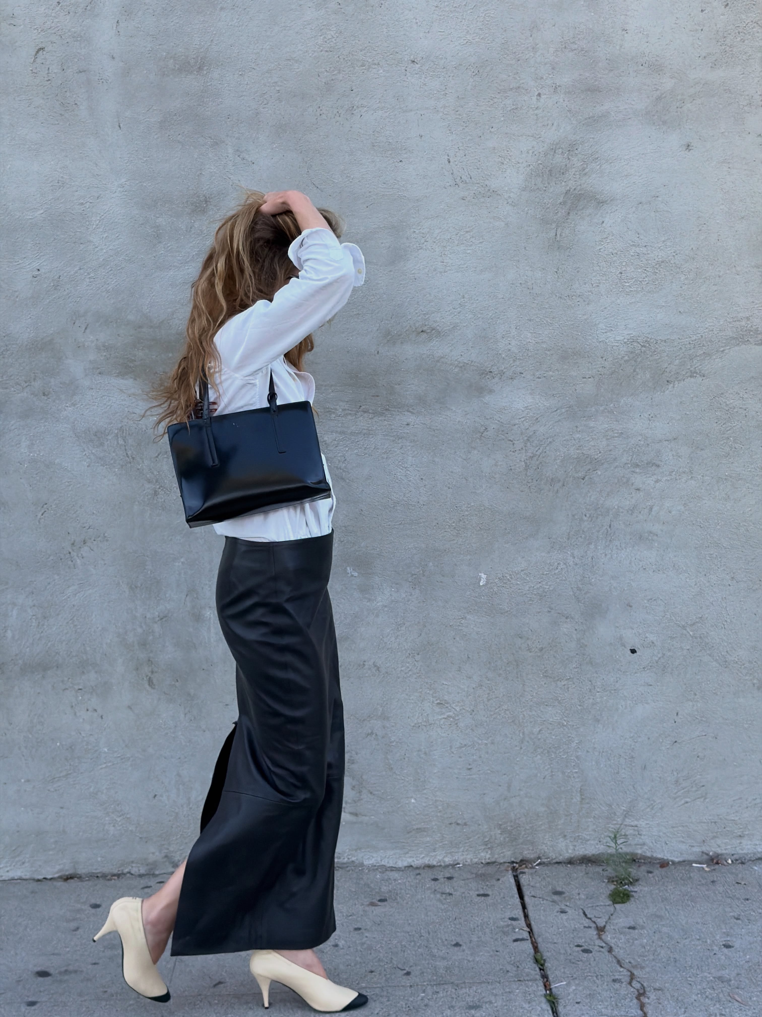 Eliza Huber wearing a button-down shirt with a leather maxi skirt and pumps.