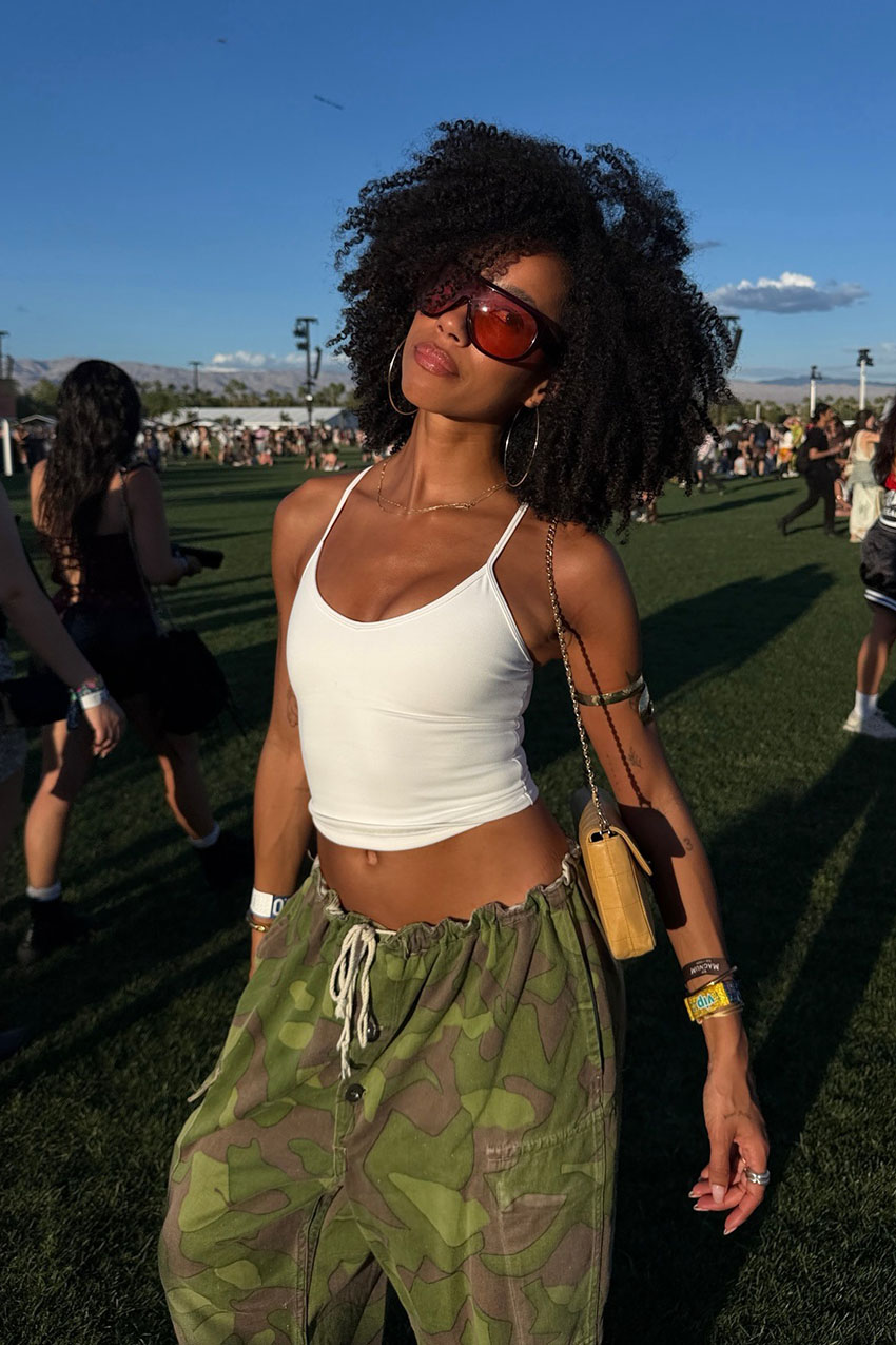 A woman wearing a white tank top and camo pants.