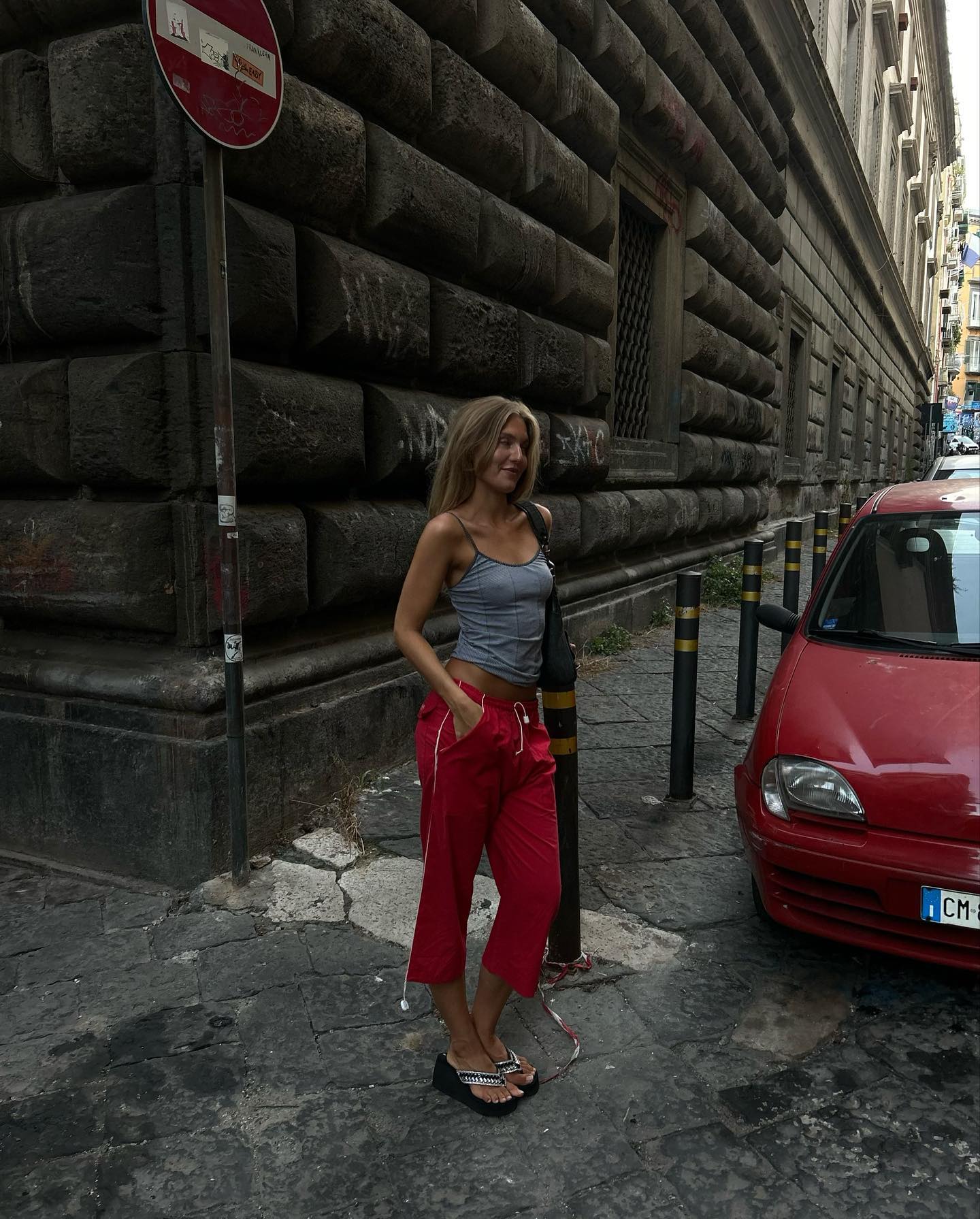 Influencer Anna Sarlvit wering a grey tank top, red relaxed capri trousers and wedge heel sandals.