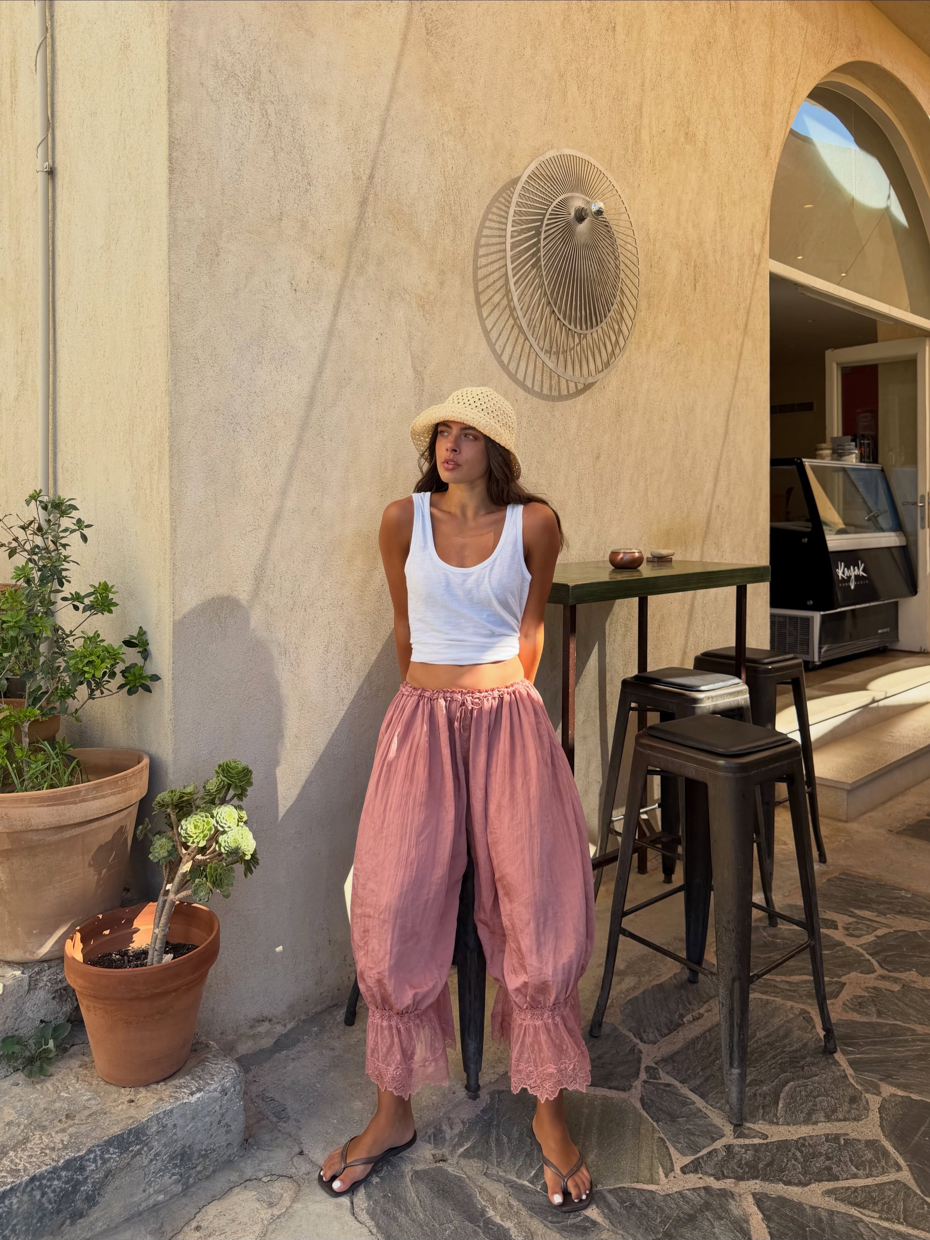 Tia in pink bloomer trousers, white vest and sun hat