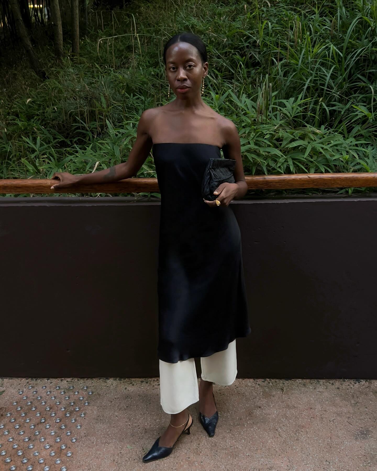 Sylvie in white satin trousers and a black dress over top