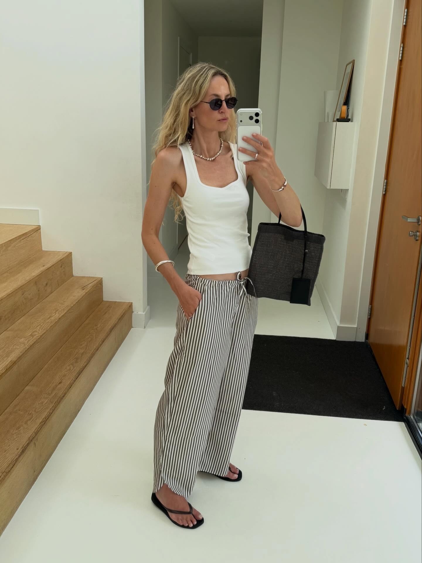 Influencer wearing a tank top, low-rise drawstring pants, and flip-flops