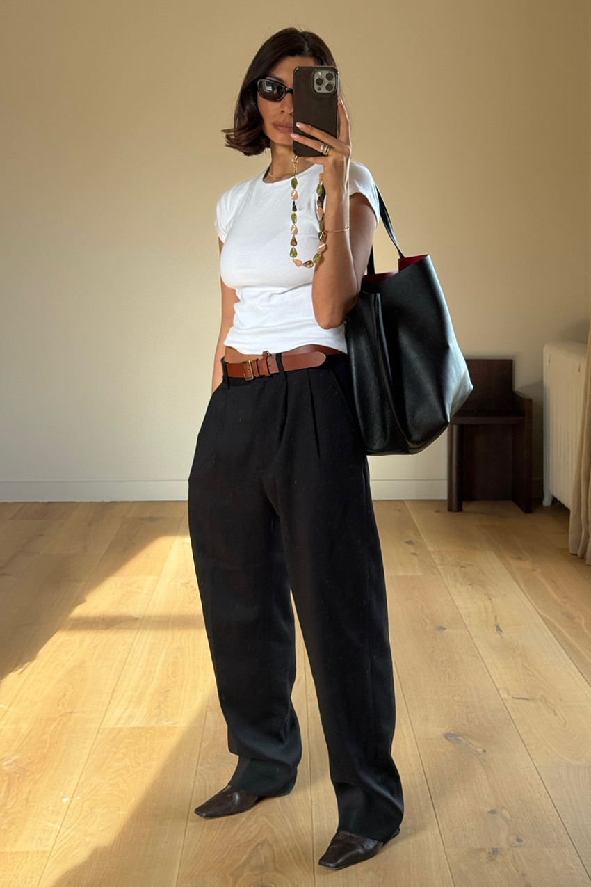 a woman wearing a white baby tee with black trousers and brown boots