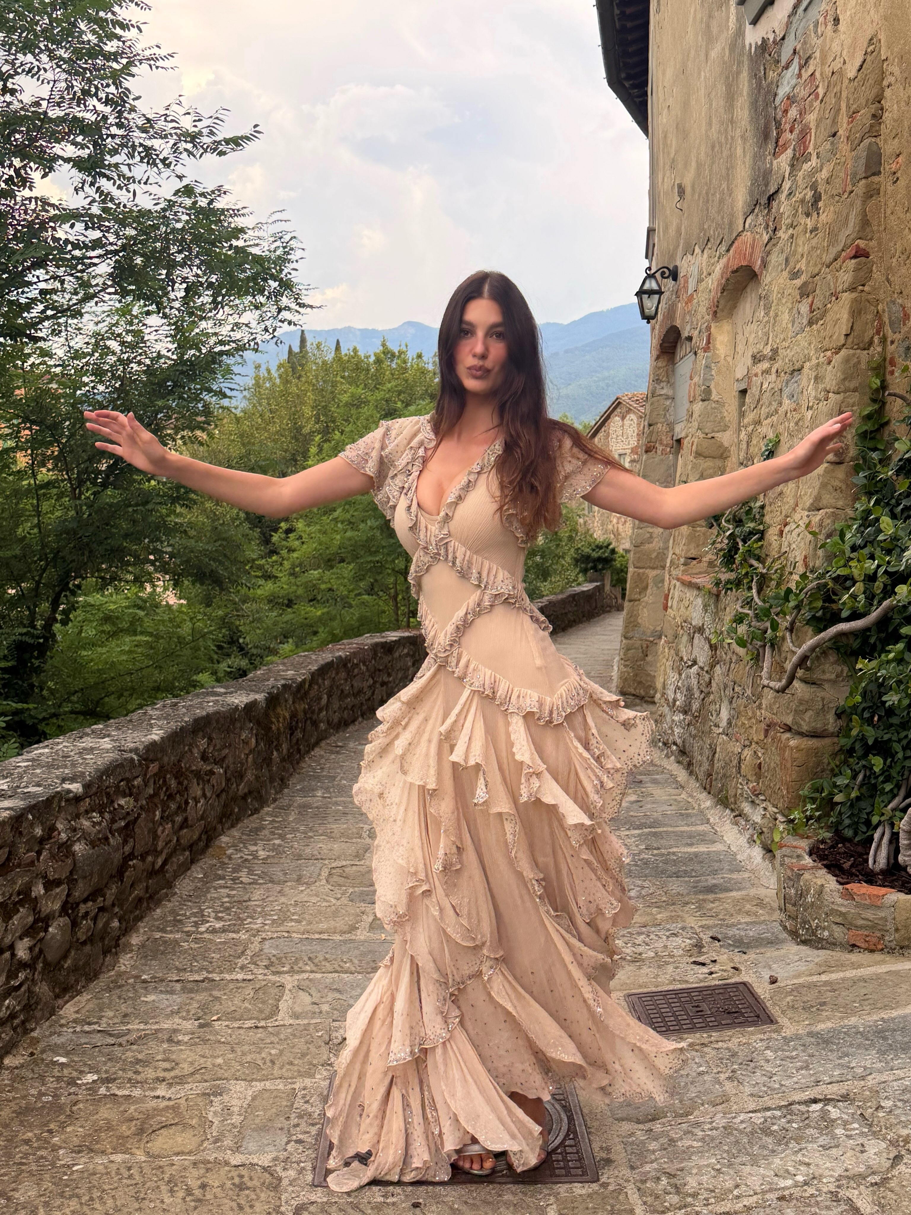 Camila Morrone wears a pink dress with ruffles to a wedding in Tuscany.