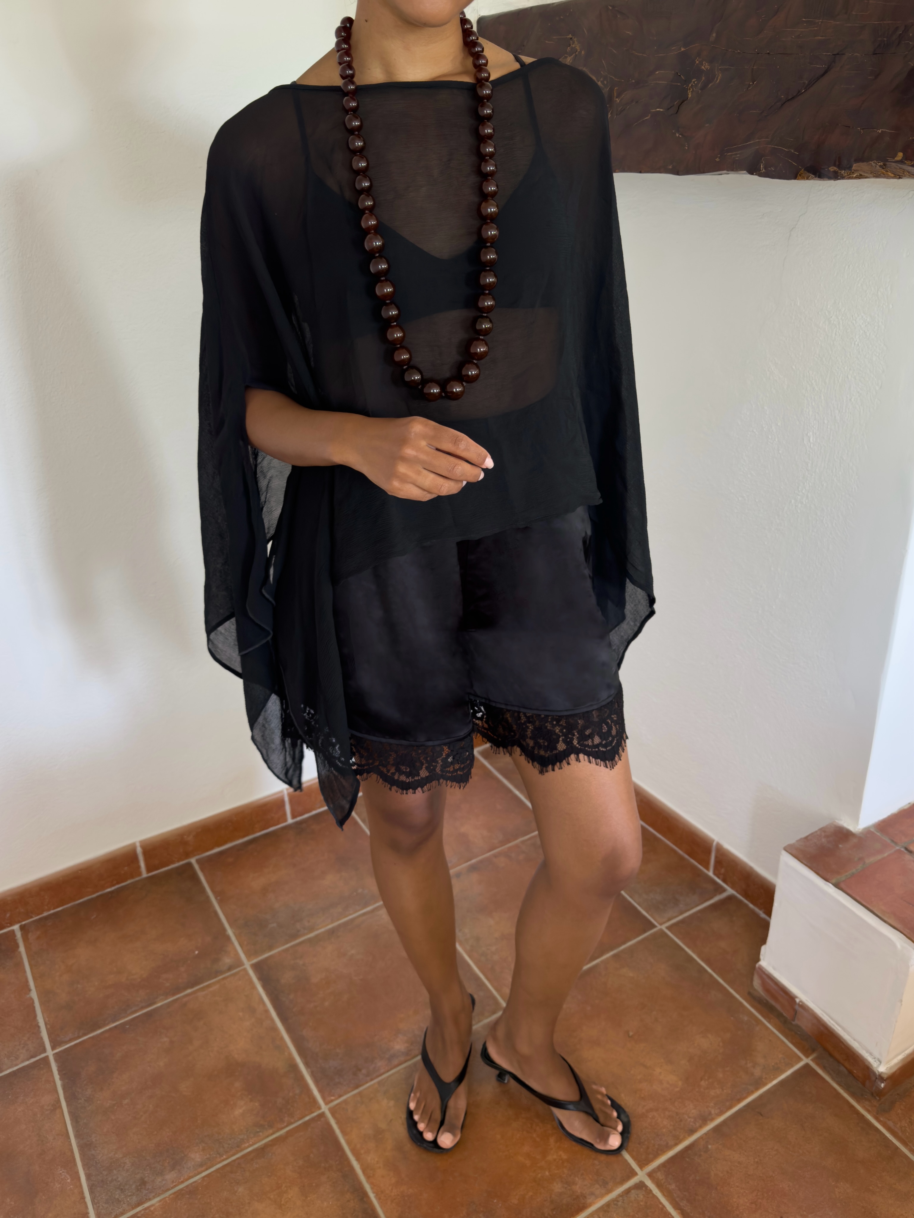 Influencer Ingrid Fagerli Edvinsen wearing a sheer top, lace-hem shorts, thong sandals and beaded necklace.