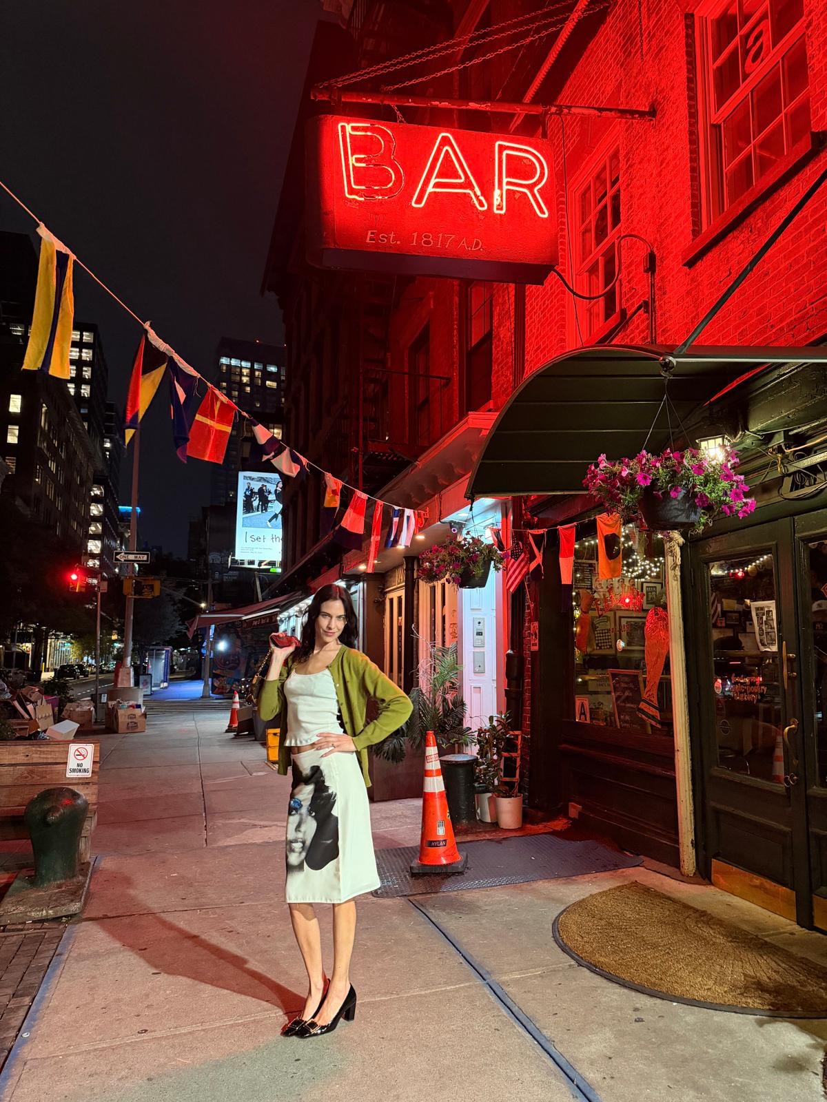 An image of @alexachung  wearing Versace's face skirt with a green cardigan whilst in New York.