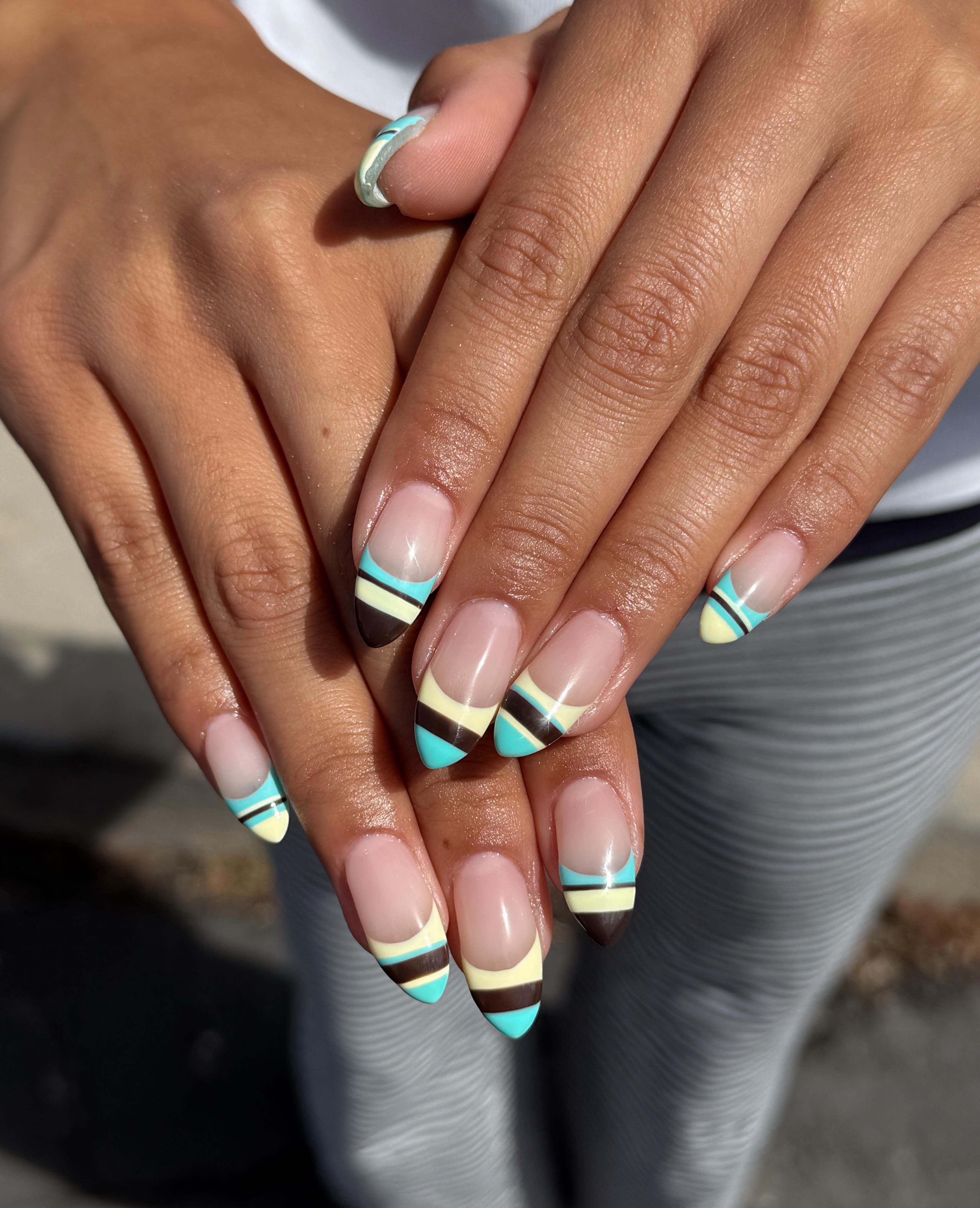 A close-up of turquoise, brown and yellow striped nail art