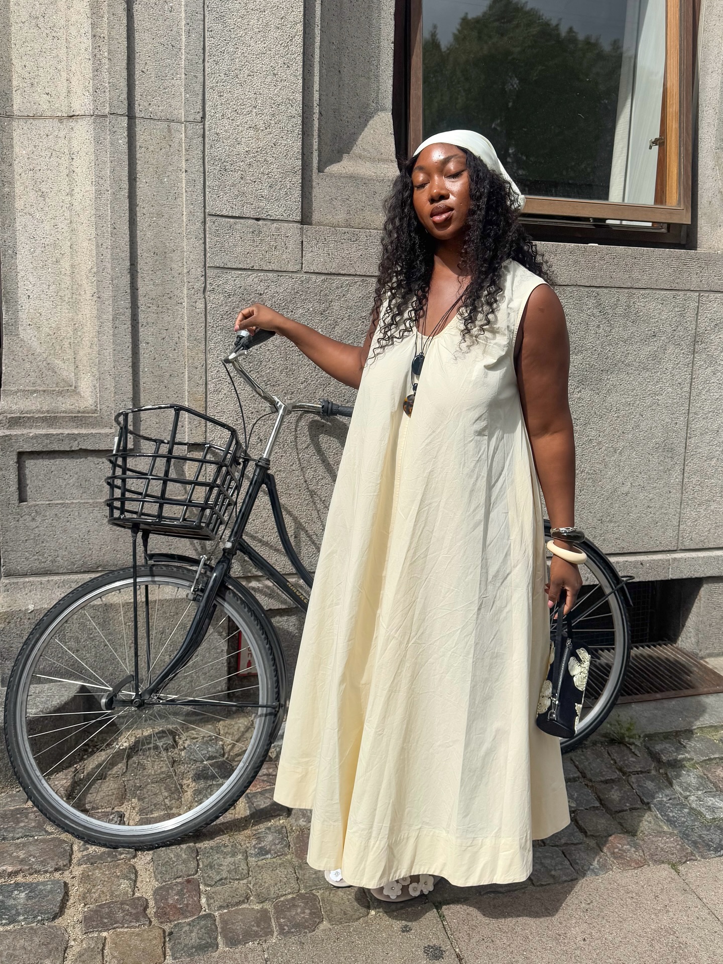 An image of an influencer wearing a cream-coloured maxi dress and matching head scarf in Copenhagen