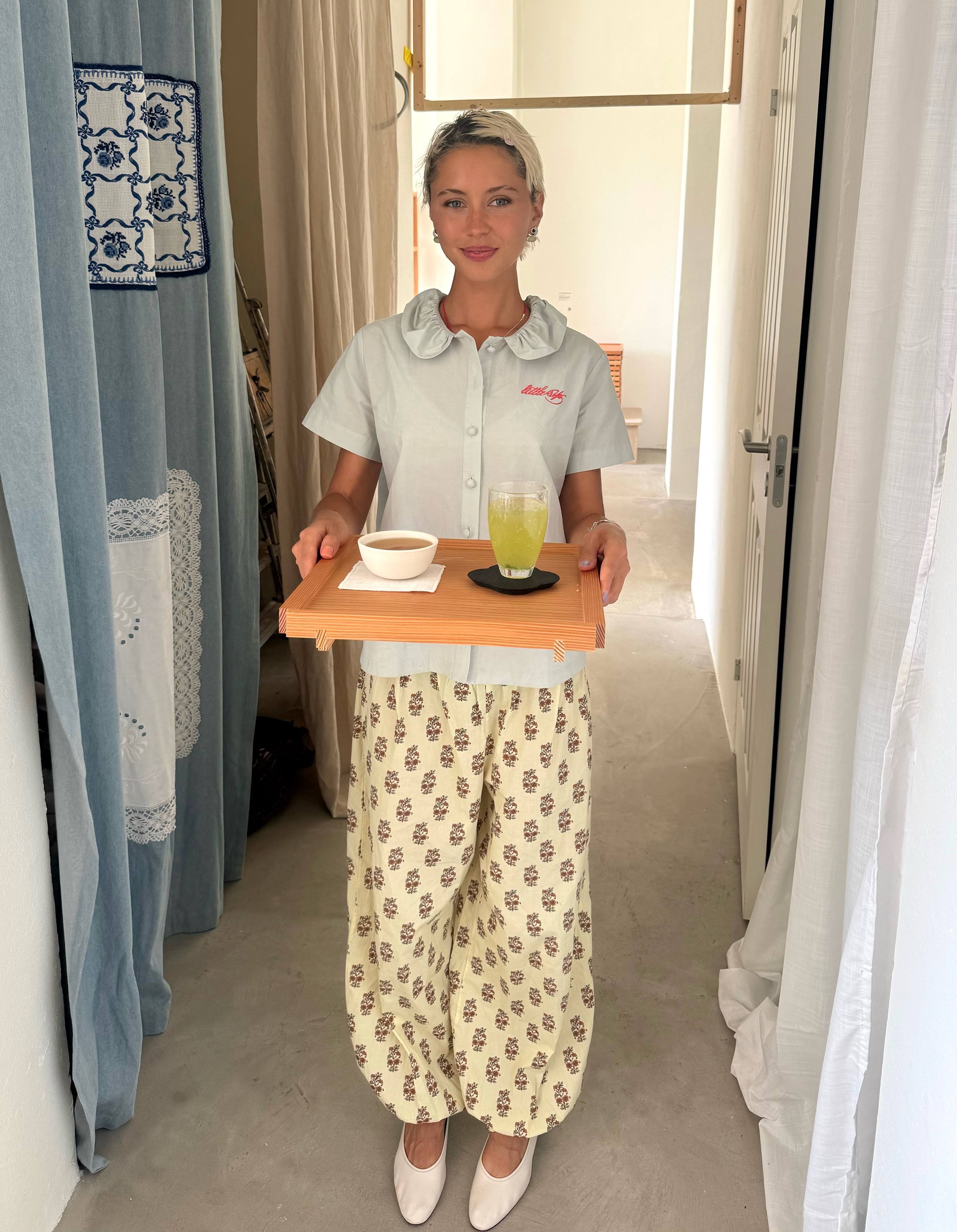 Iris Law wears balloon trousers with a button-down blouse and white ballet flats.