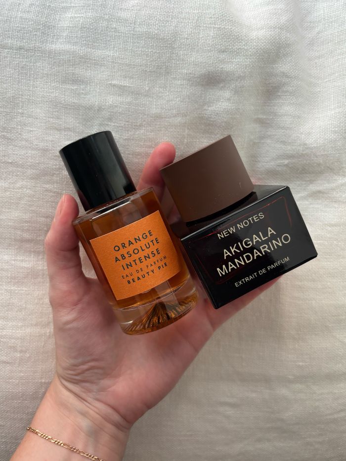 Deputy beauty editor Grace Lindsay holding two of the best orange perfumes