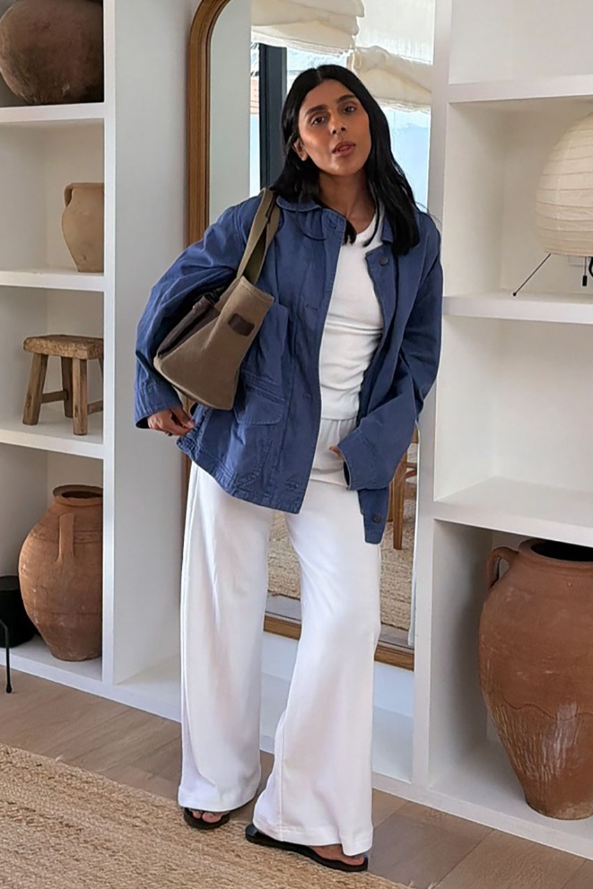 a woman wearing a blue button-down, white tee, white pants, and flip-flops