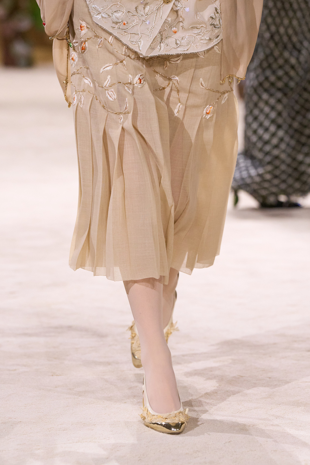 A model walking in the Chanel F/W 26 Haute Couture Show in Paris wearing metallic heels.