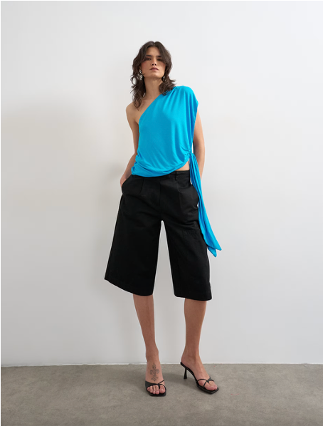 A model wears a turquoise Topshop top and black culottes.