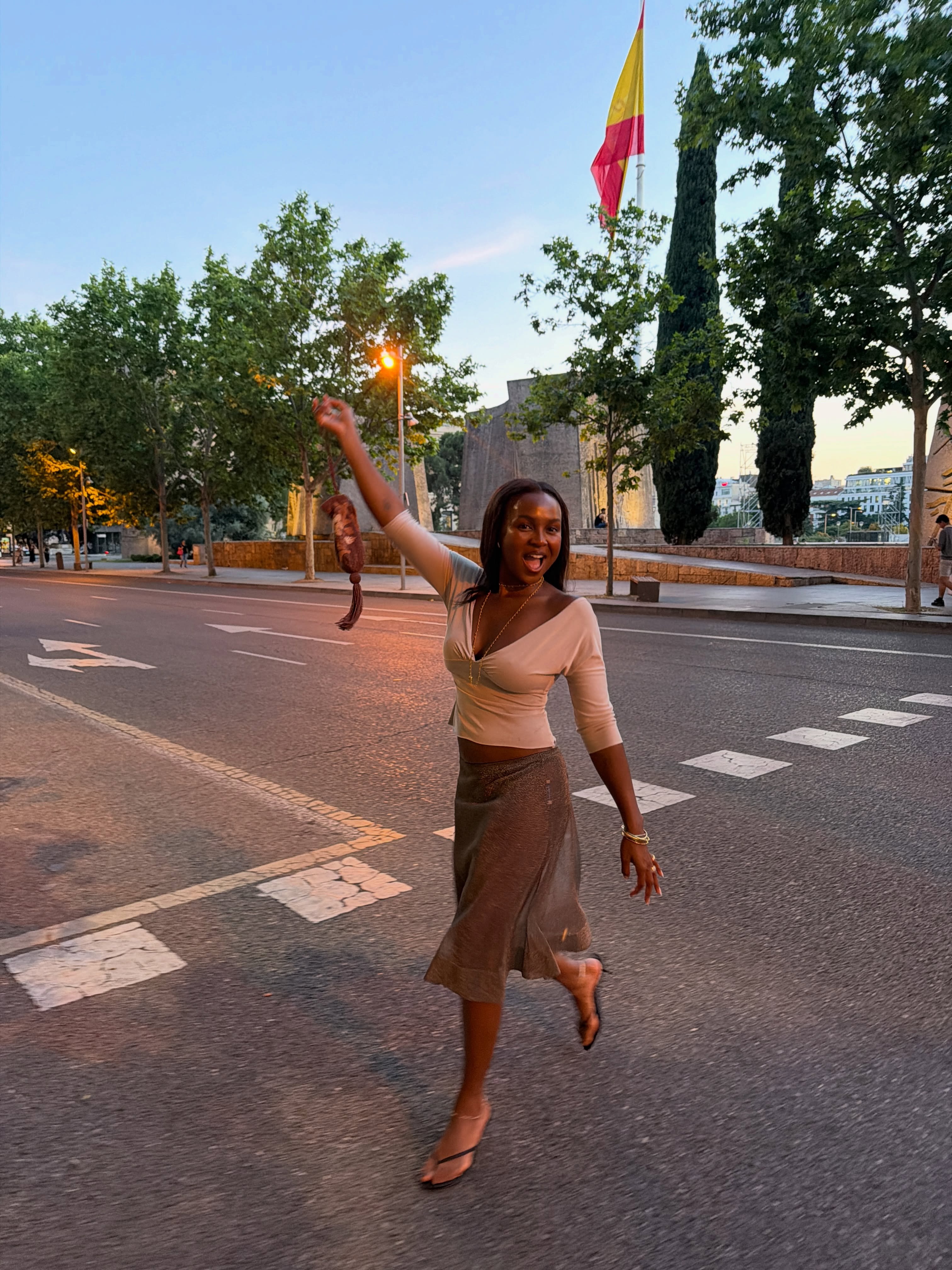 @devapollon wearing a V-neck top and knee-length skirt with heeled thong sandals.