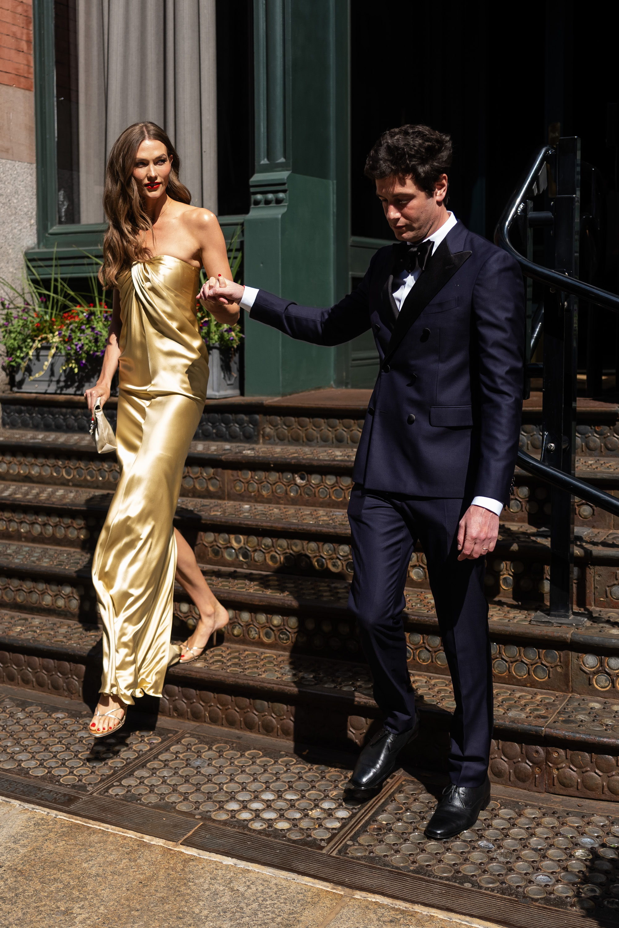 Karlie Kloss wears a gold strapless dress to Taylor Swift's wedding, along with a pair of Femme LA Sicilian Slipper Sandals that Hailey Bieber also owns
