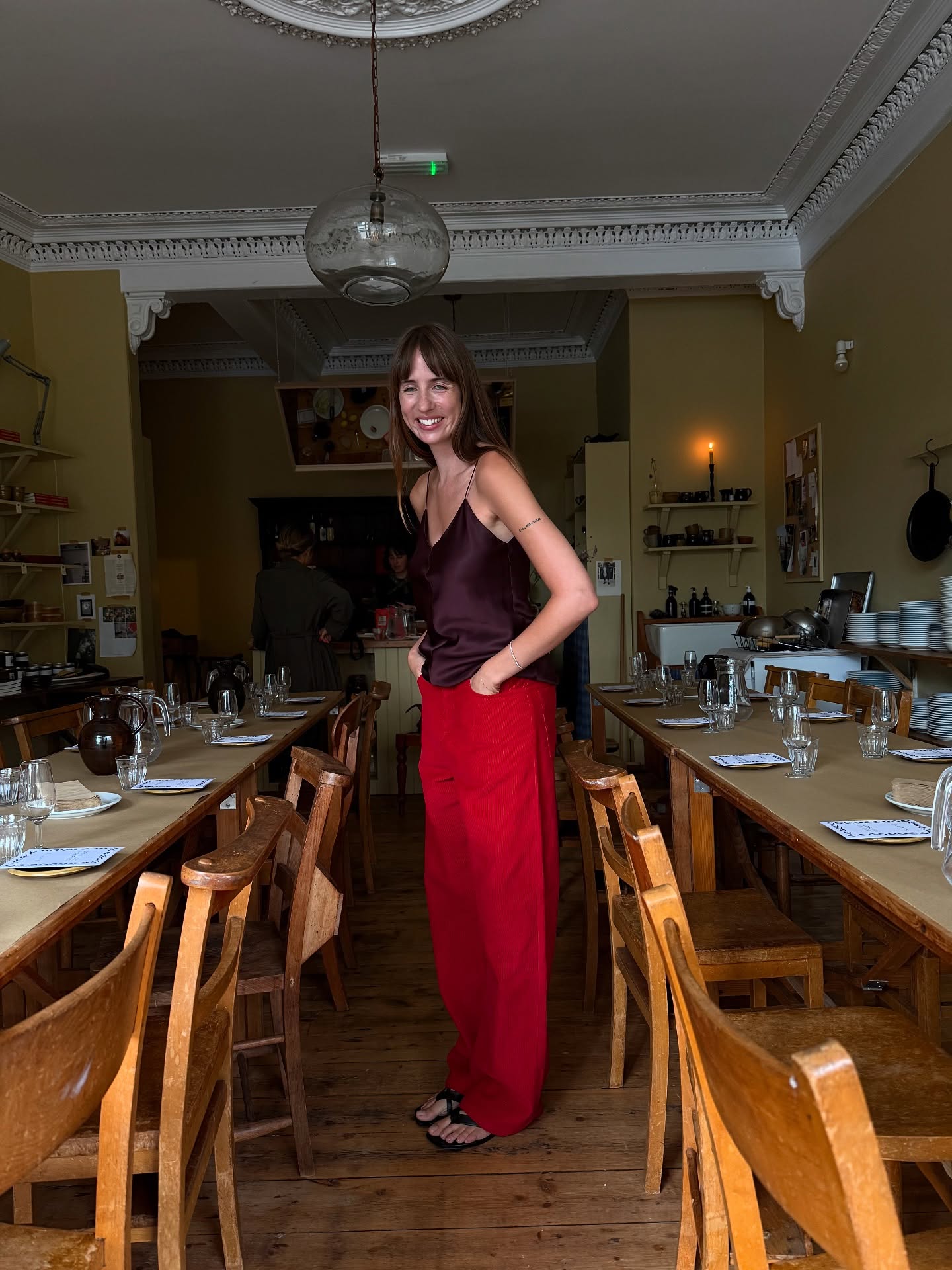 An image of @lizzyhadfield wearing red jeans with chocolate brown shoes.