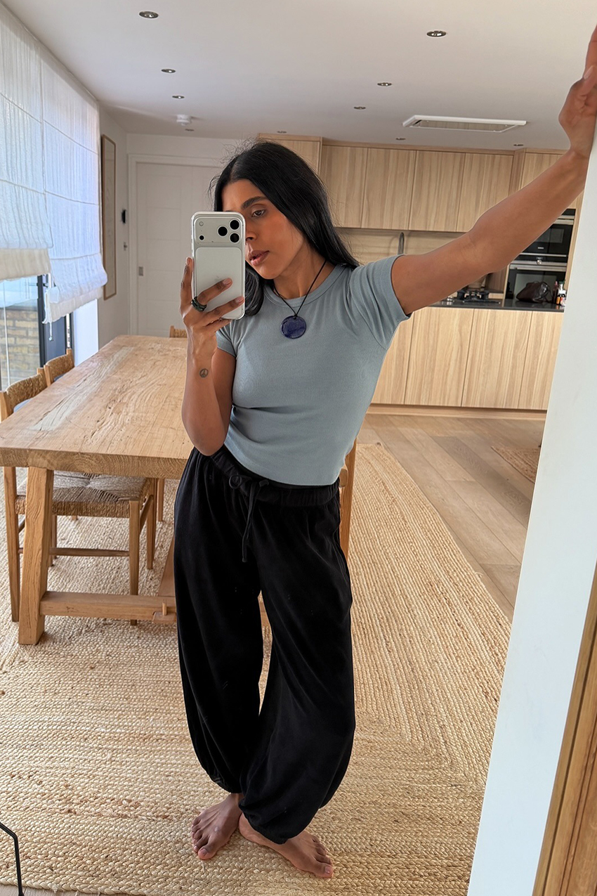 a woman wearing a gray baby tee and black pants