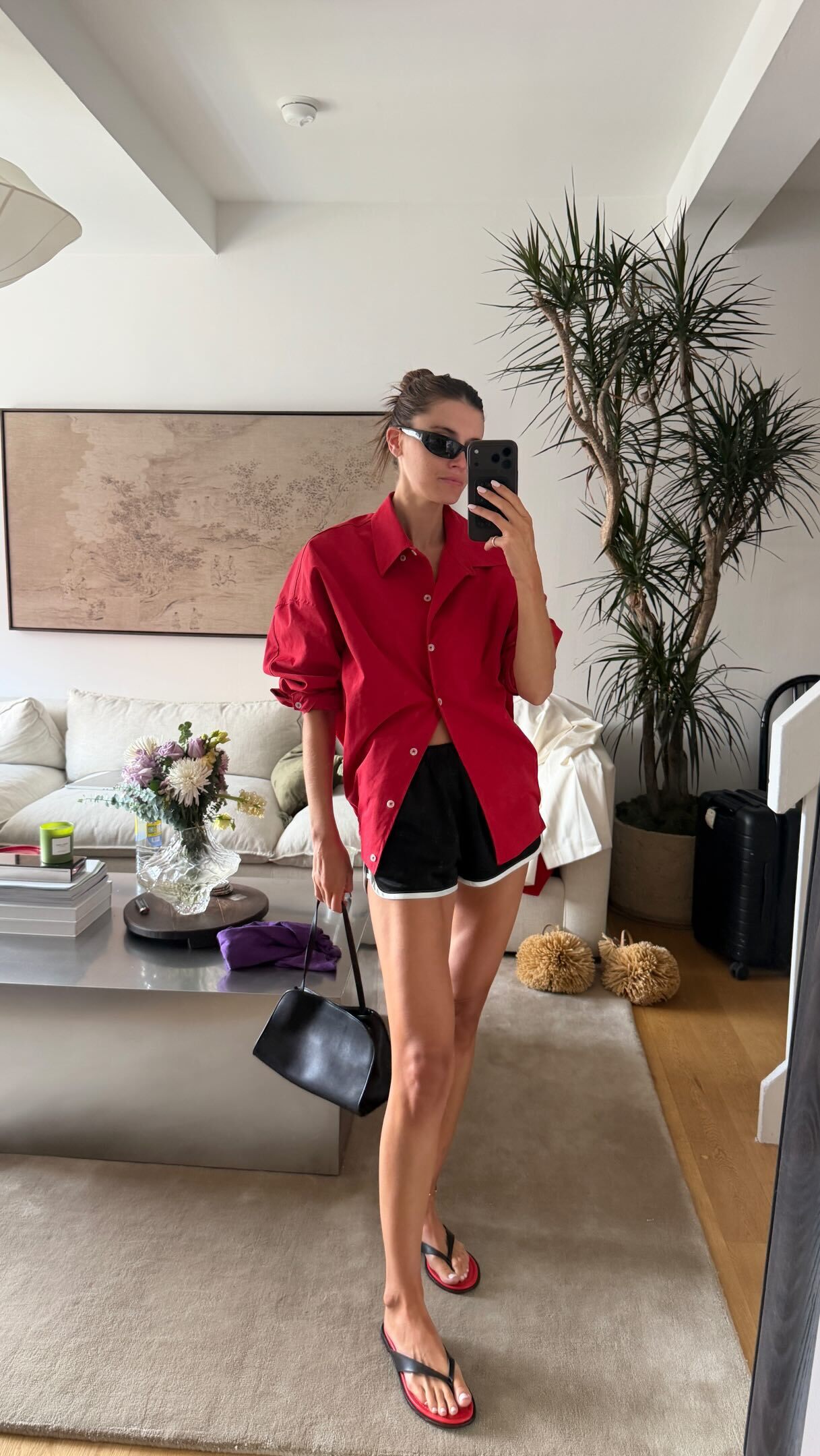 @cocoschiffer wears the reformation Jessie Sandal in black and red. She pairs them with a red shirt and black running shorts in a recent image on her Instagram.