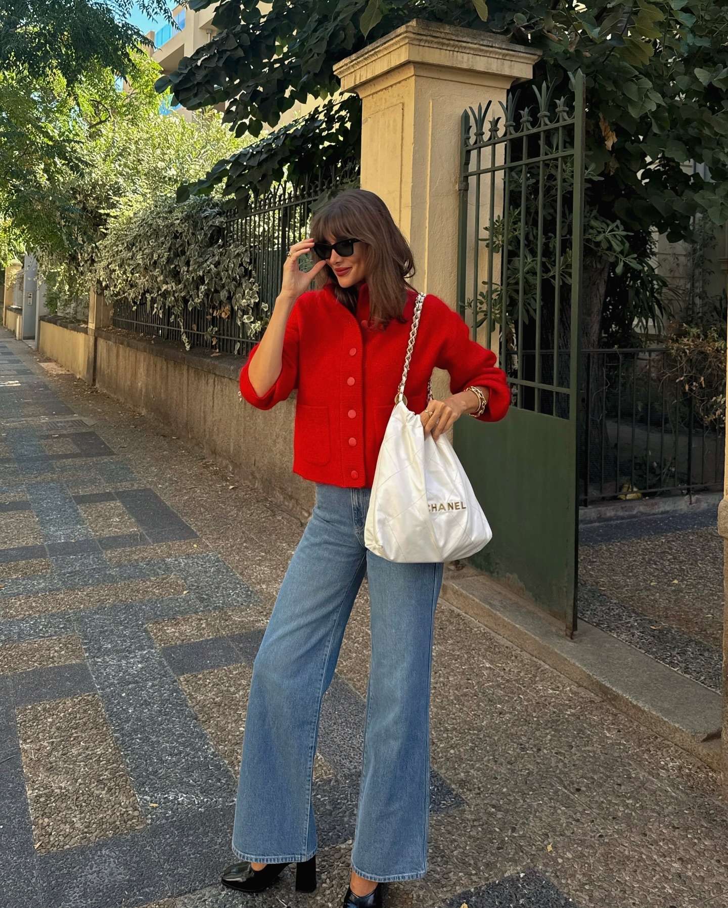 Influencer @juliesfi wears wide leg jeans with black high heels and a red jacket.