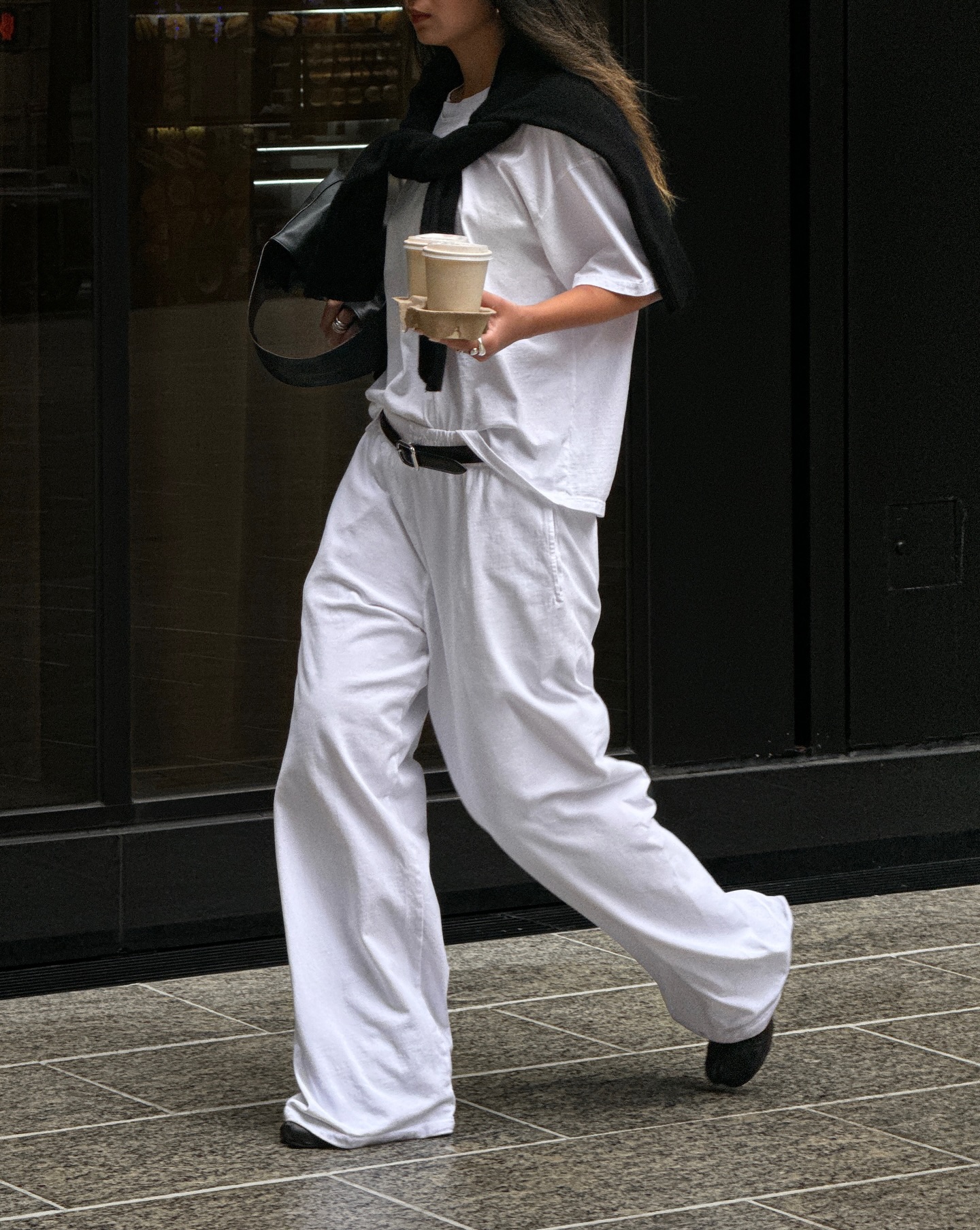 An image of @thecarolinelin wearing a rich-looking airport outfit including an oversized t-shirt, loose white pants and trainers.