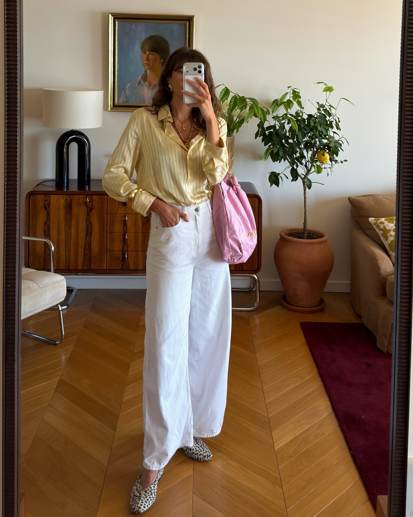 French influencer wearing a yellow button-down, white jeans, and a pink Chanel bag with animal-print ballet flats