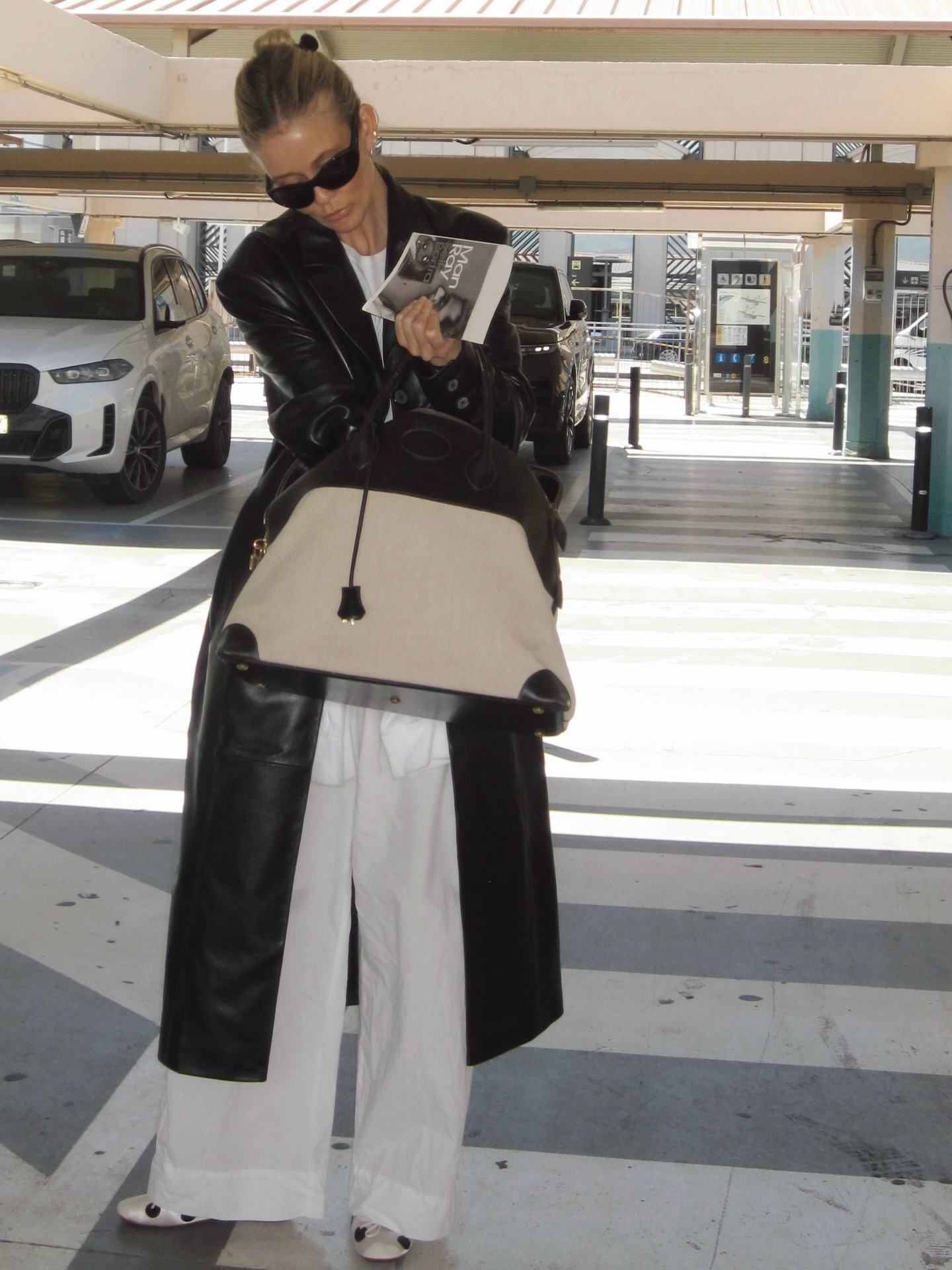 An image of @josefinehj wearing a rich-looking airport outfit including a leather coat, cotton trousers and polka-dot ballet flats.