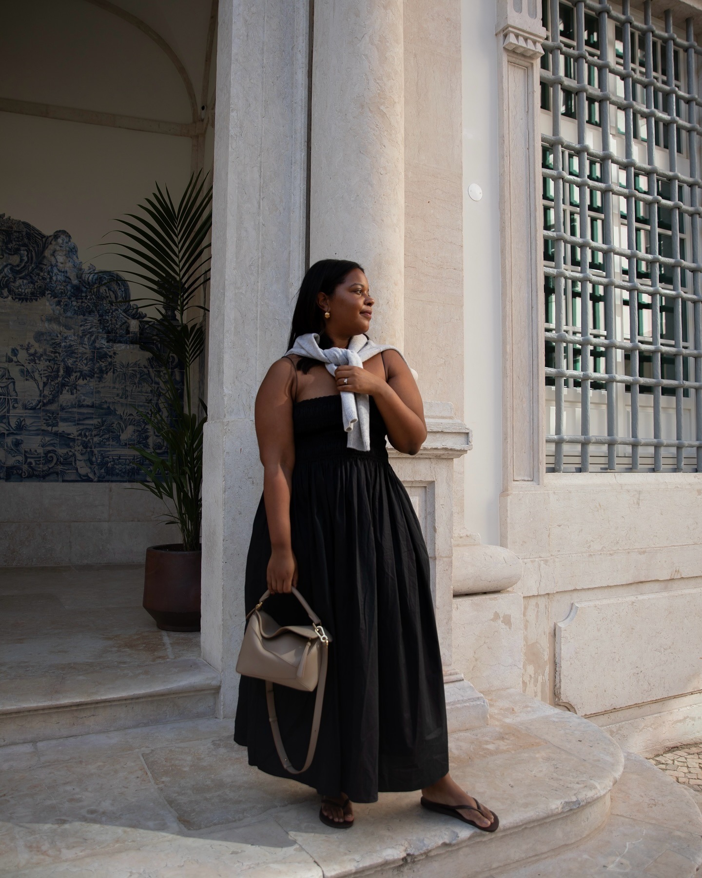 Woman wears black shirred dress from Matteau, taupe Loewe Puzzle bag