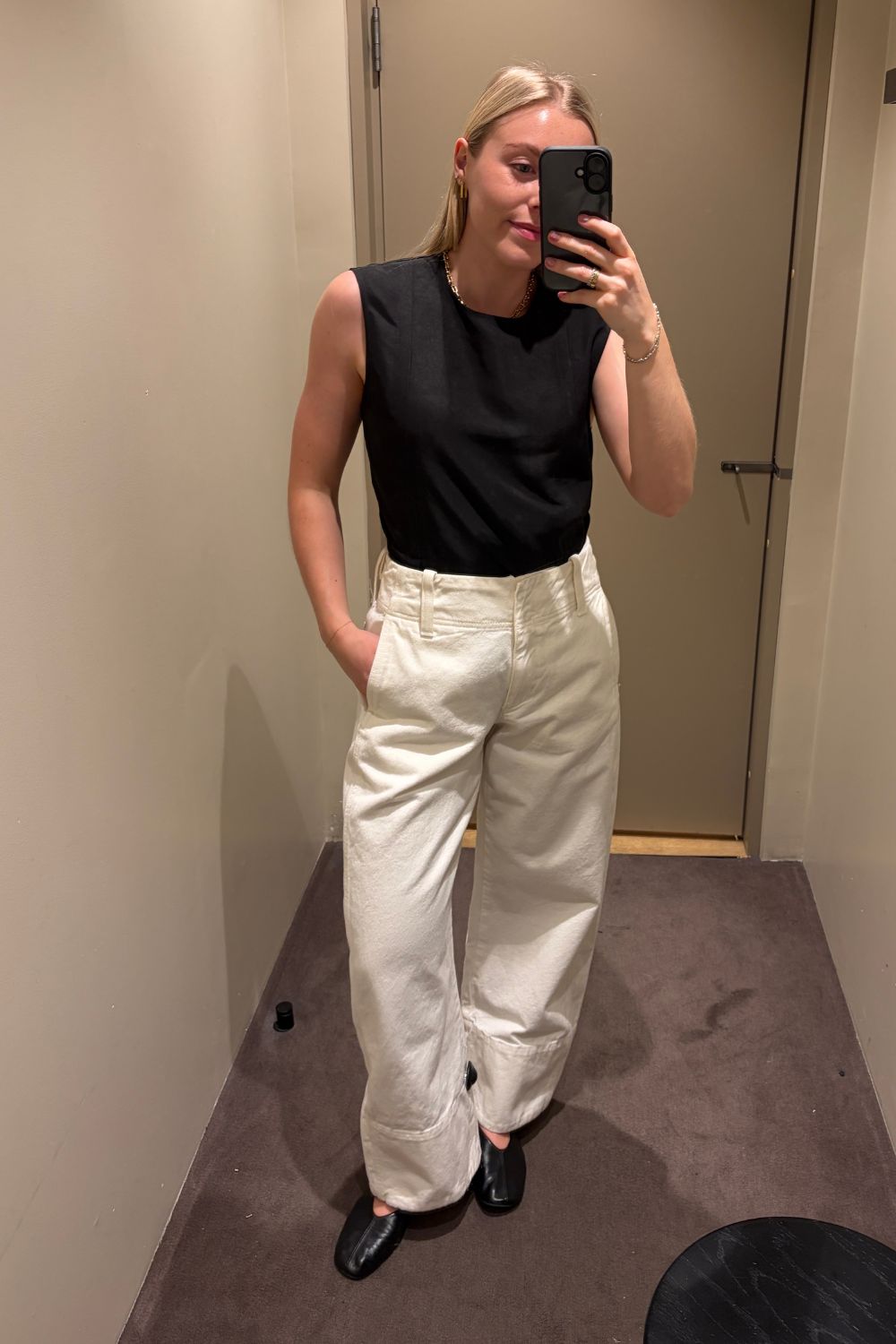 Woman wears black top, white jeans and ballet flats