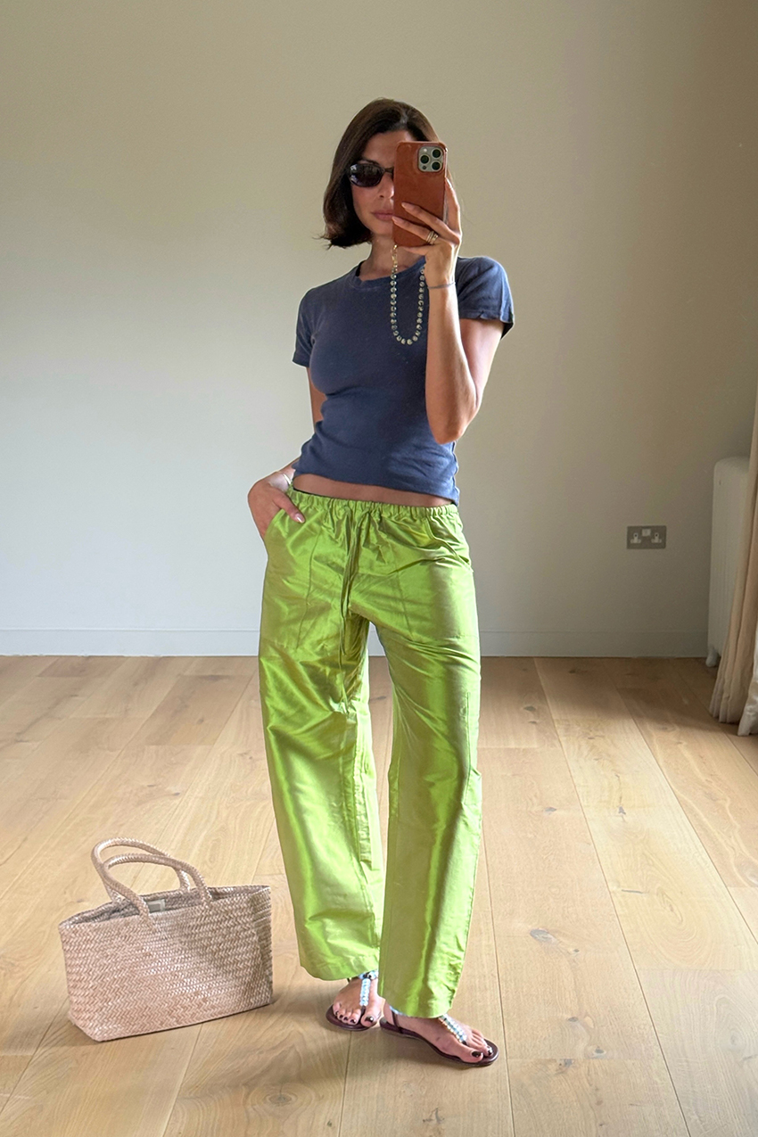 a woman wearing a gray baby tee, green pants, beaded sandals