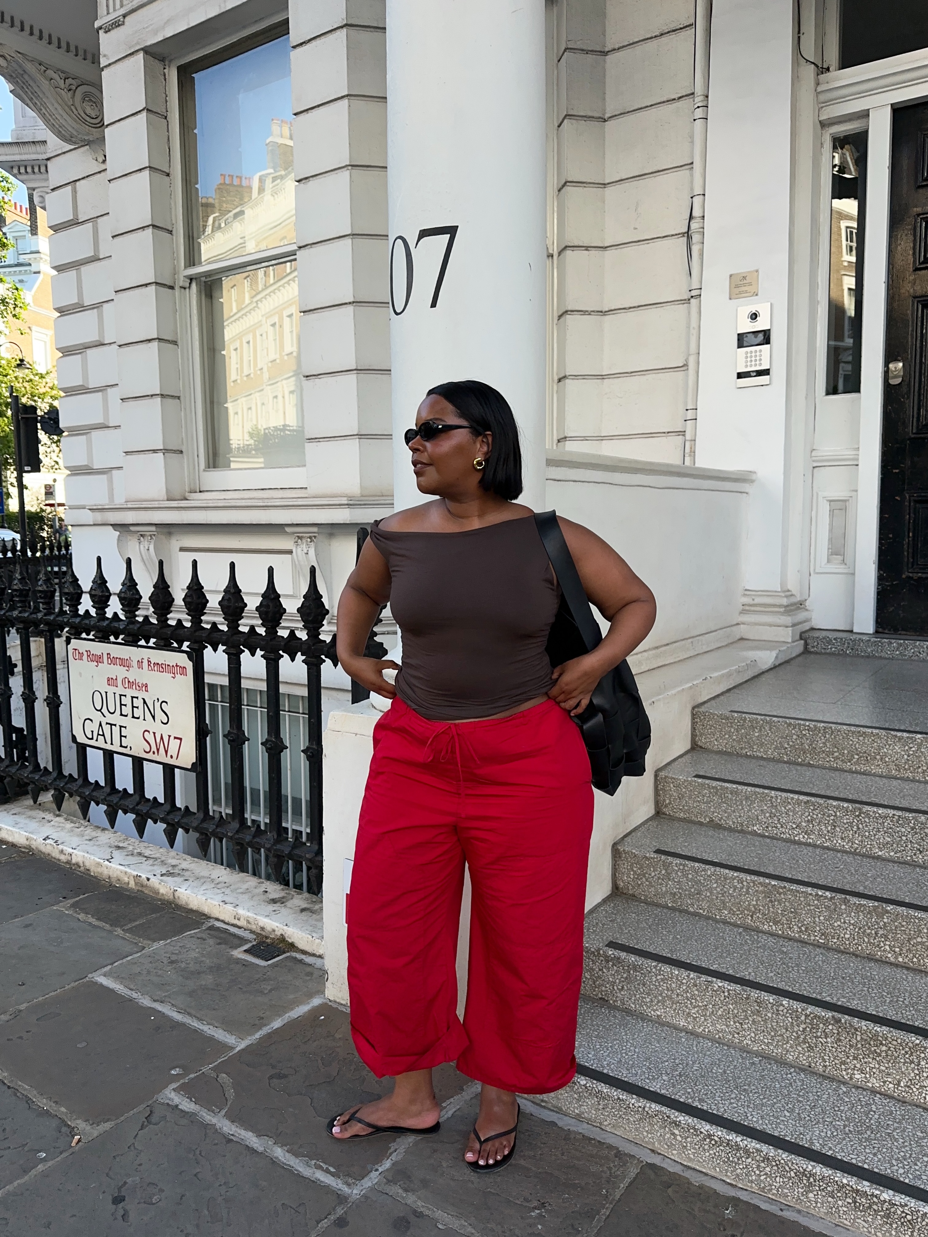 Karina wears red trousers and black flip-flops.