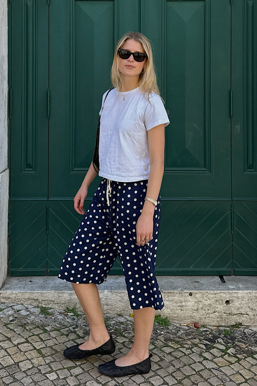 a woman wearing a white baby tee, polka dot carpris and black flats