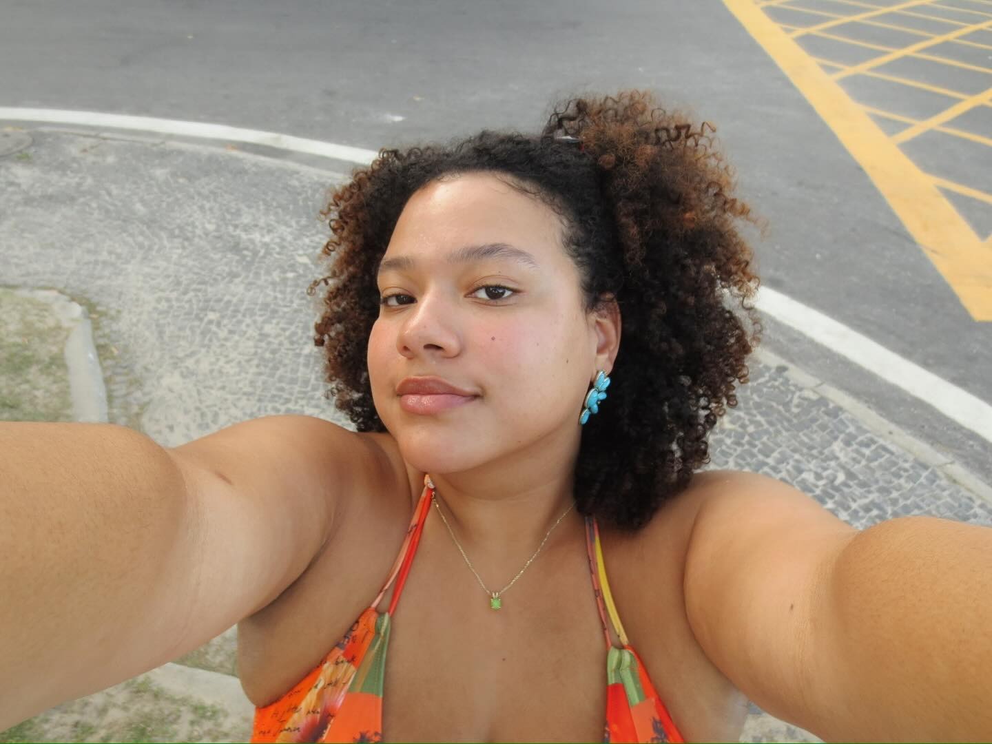 A woman with curly, spiced brunette hair taking a selfie