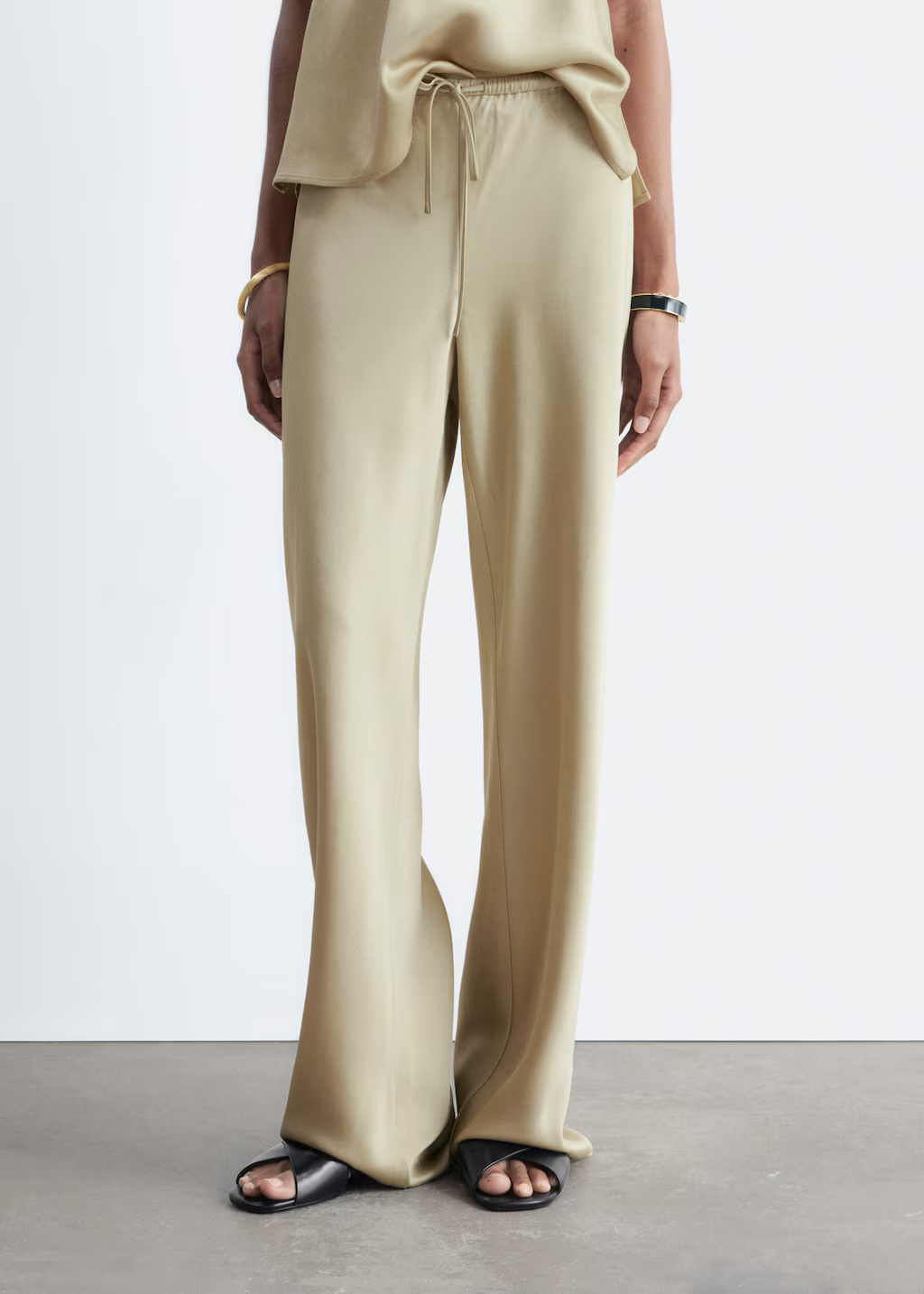 A model wearing a pair of beige & Other Stories satin trousers