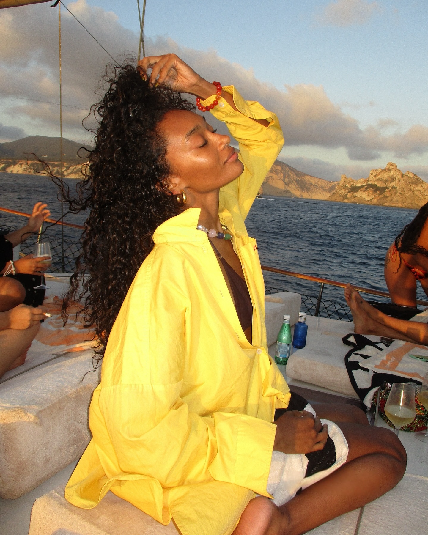 A girl wearing a large yellow button-down shirt on a boat.