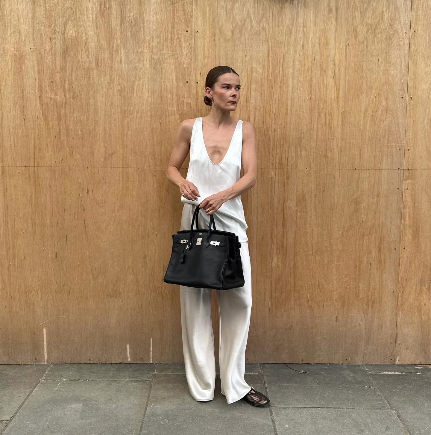 An image of @rikkekrefting wearing a rich-looking airport outfit including a silk scoop-neck top, satin trousers and mesh ballet flats.
