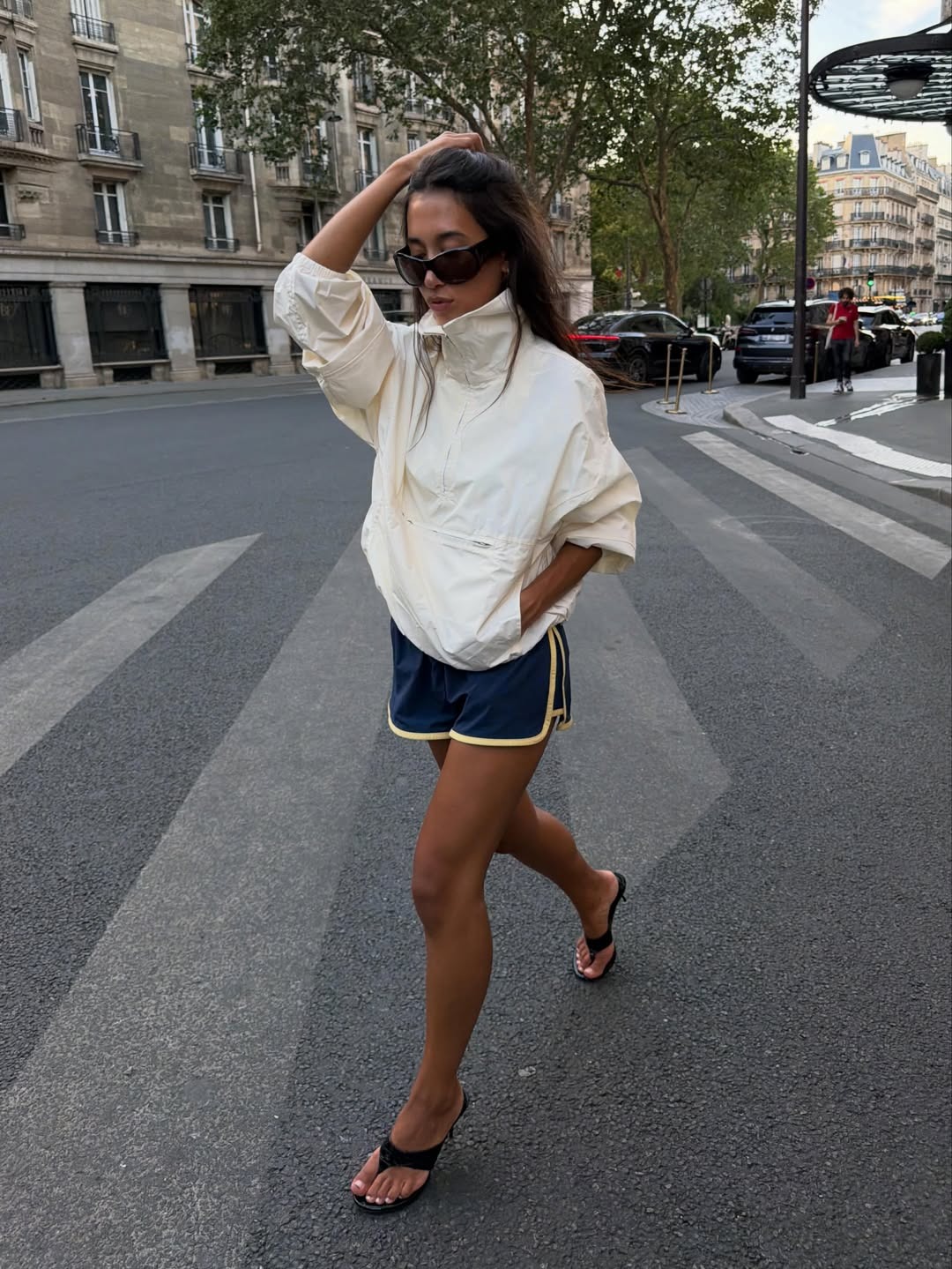Woman wearing track shorts and a funnel-neck jacket.