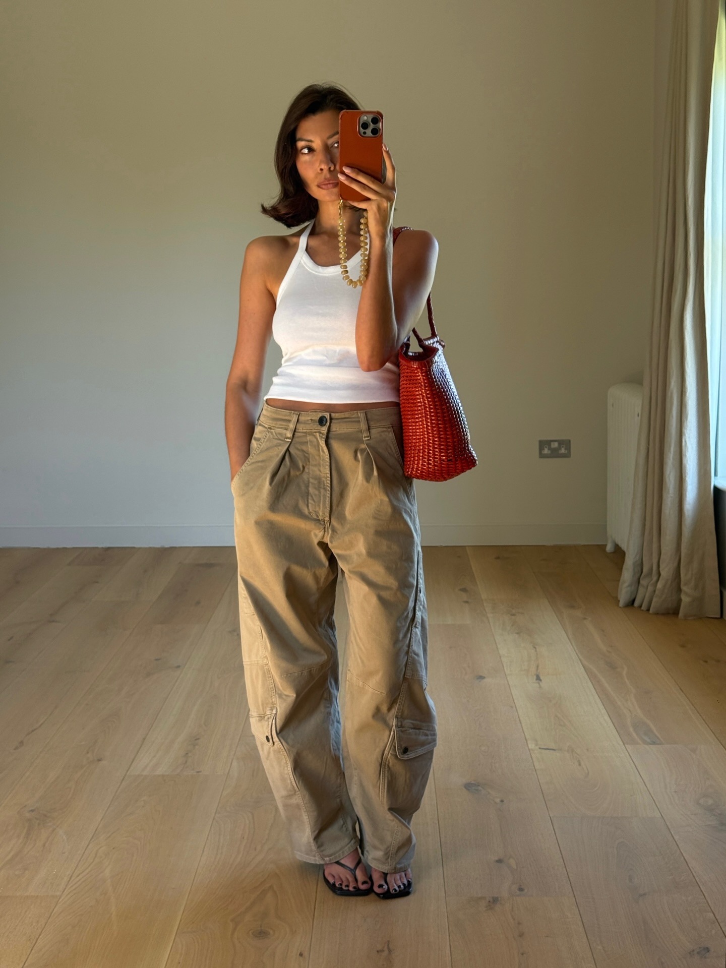 Influencer wearing dark beige pants with a white tank and flip-flops