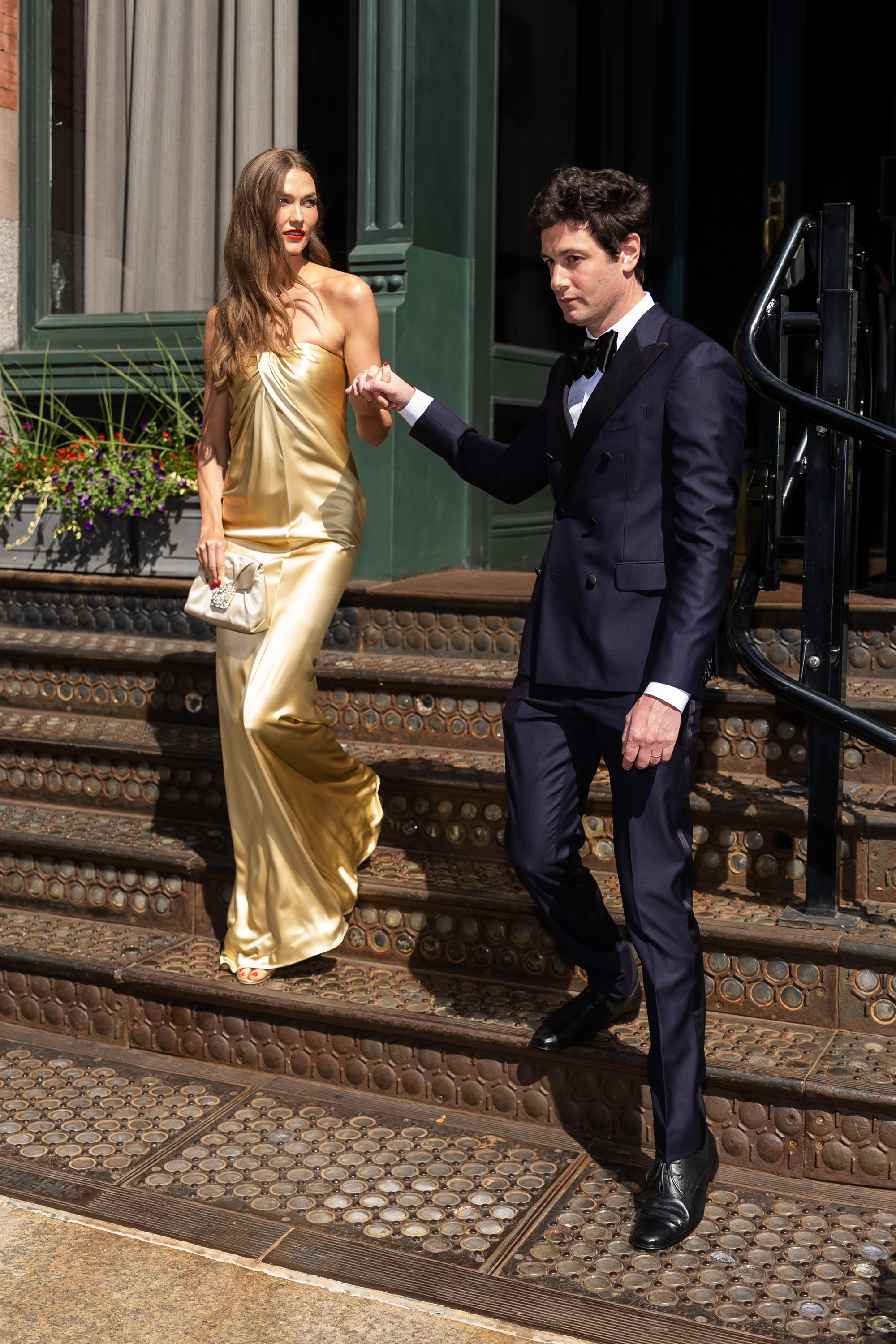 Karlie Kloss wears a gold strapless dress to Taylor Swift's wedding, along with a pair of Femme LA Sicilian Slipper Sandals that Hailey Bieber also owns