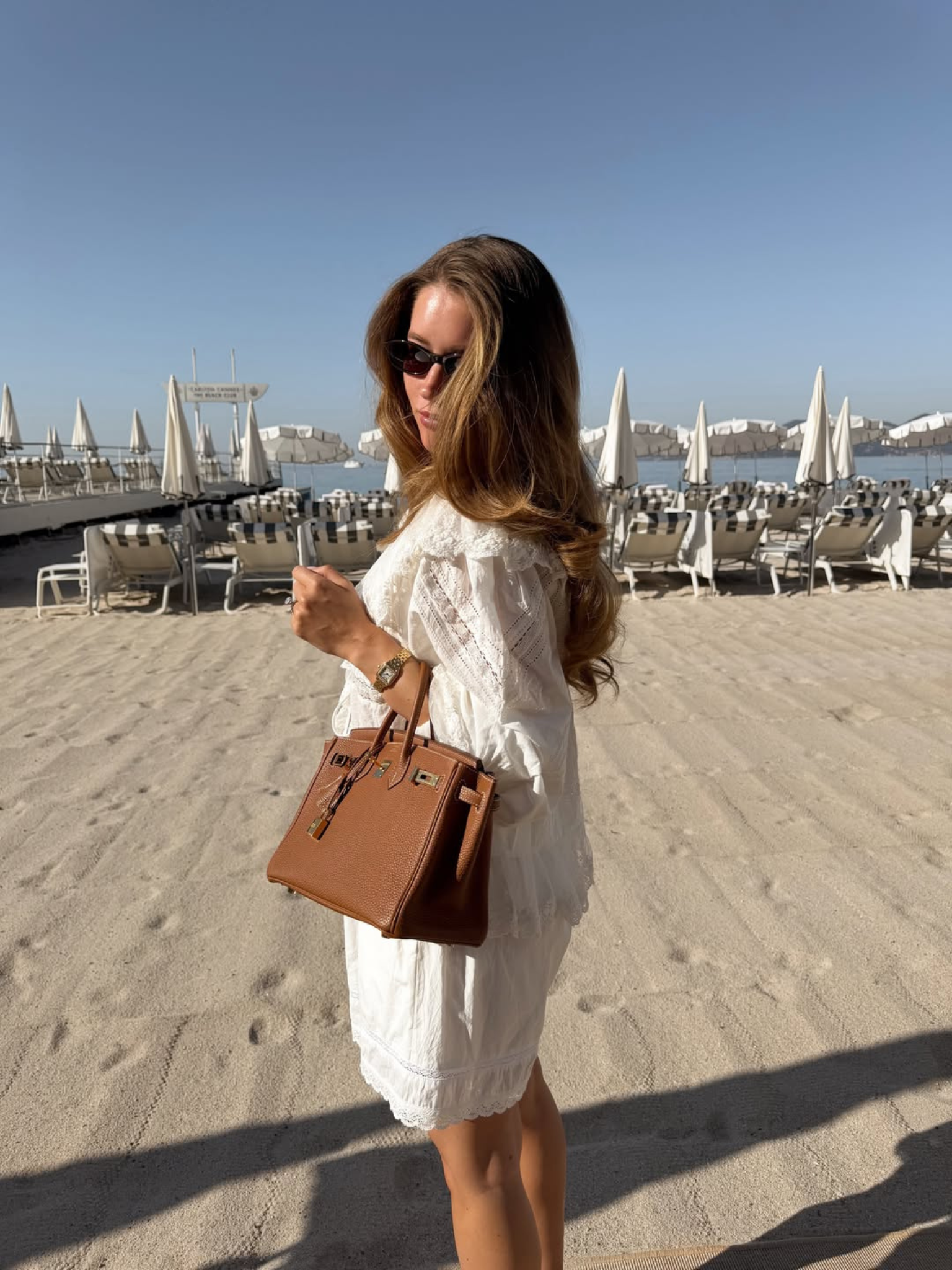 A woman with soft brunette hair standing on a beach