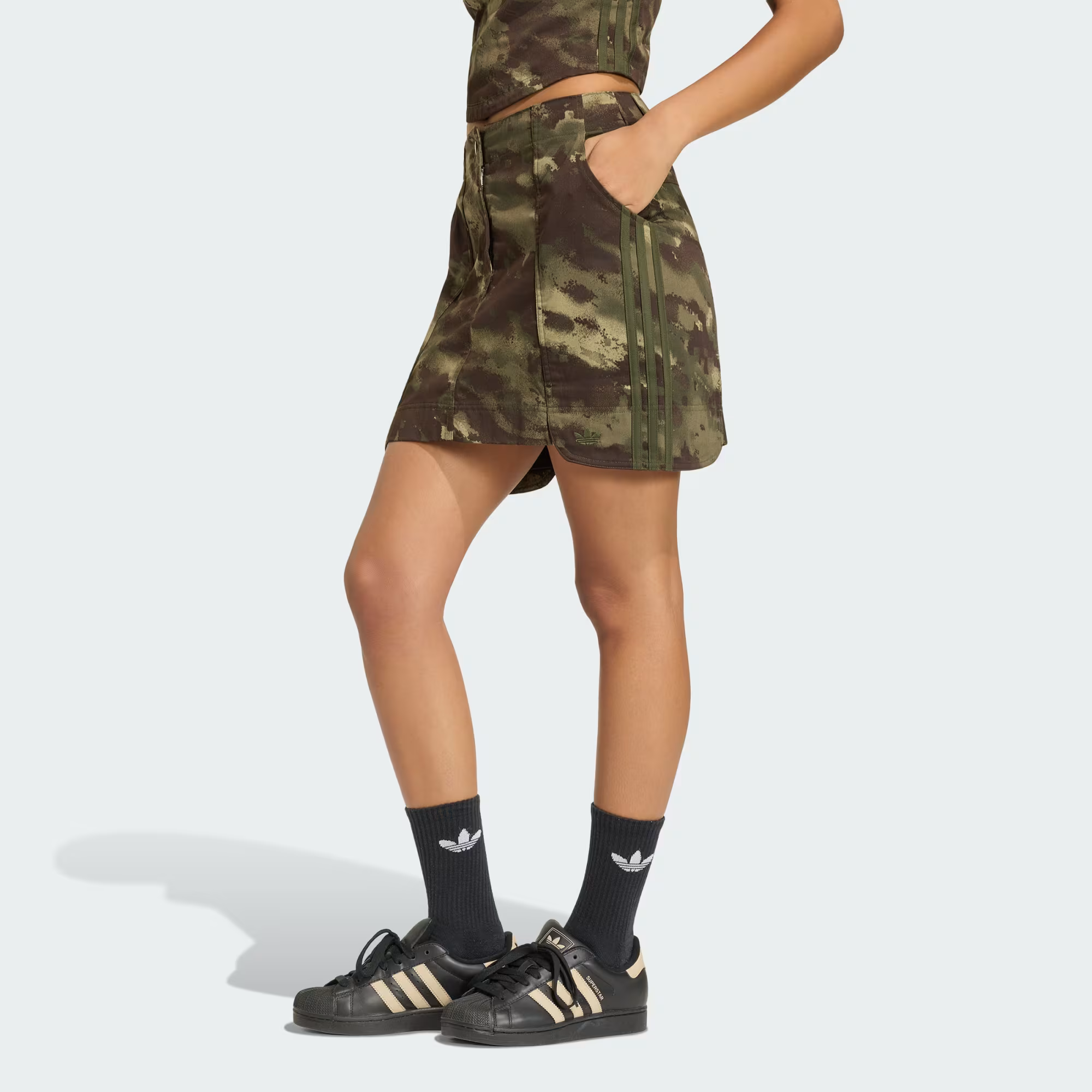 A model wearing an Adidas camo print mini skirt.